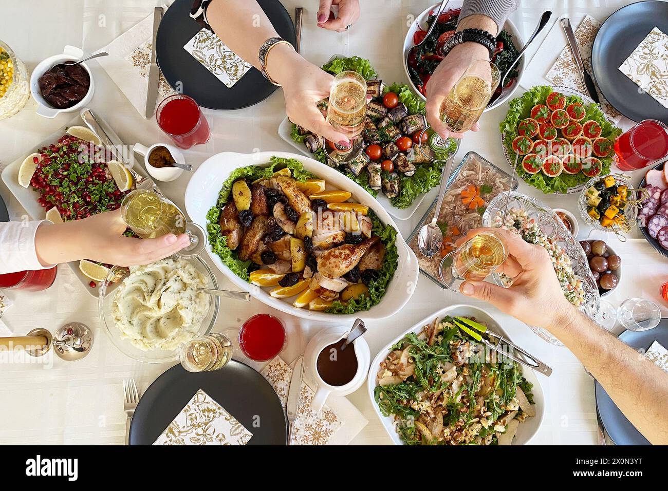 Tisch voller köstlicher Speisen auf Tellern, Blick von oben. Gebackenes Hühnchen mit Kartoffeln, Kaviar in Tartlets, Salate, verschiedene Snacks und Getränke bei einem Galadinner Stockfoto
