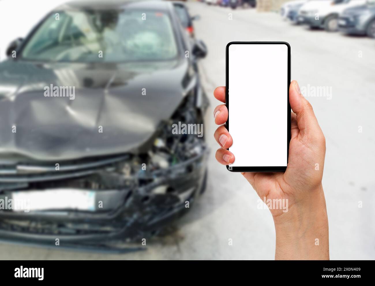 Hand mit einem leeren Bildschirm Telefon mit einem Autounfall im Hintergrund Stockfoto