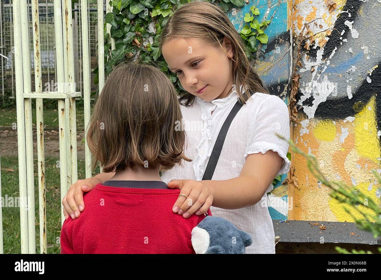 Kleine Schwester umarmt und beruhigend weinendes kleines Mädchen, damit es sich besser fühlt, Konzept von Geschwisterkind, Liebe, Beziehung, Freundschaft und Wachstum des Kindes Stockfoto