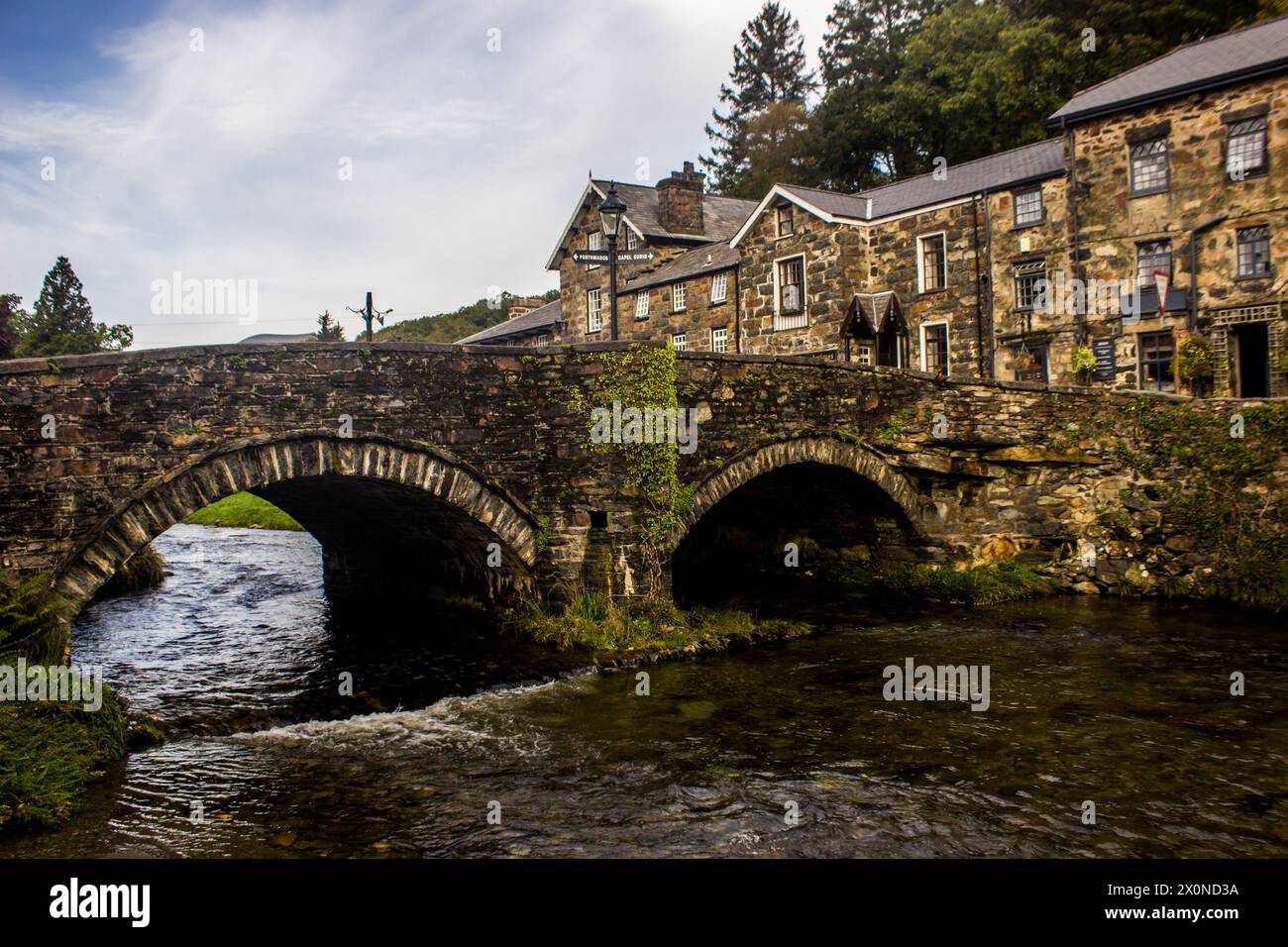 Die zweibogige Steinbrücke überquert den Fluss Colwyn in der kleinen malerischen Stadt Beddgelert im Eryri National Park, Wales Stockfoto