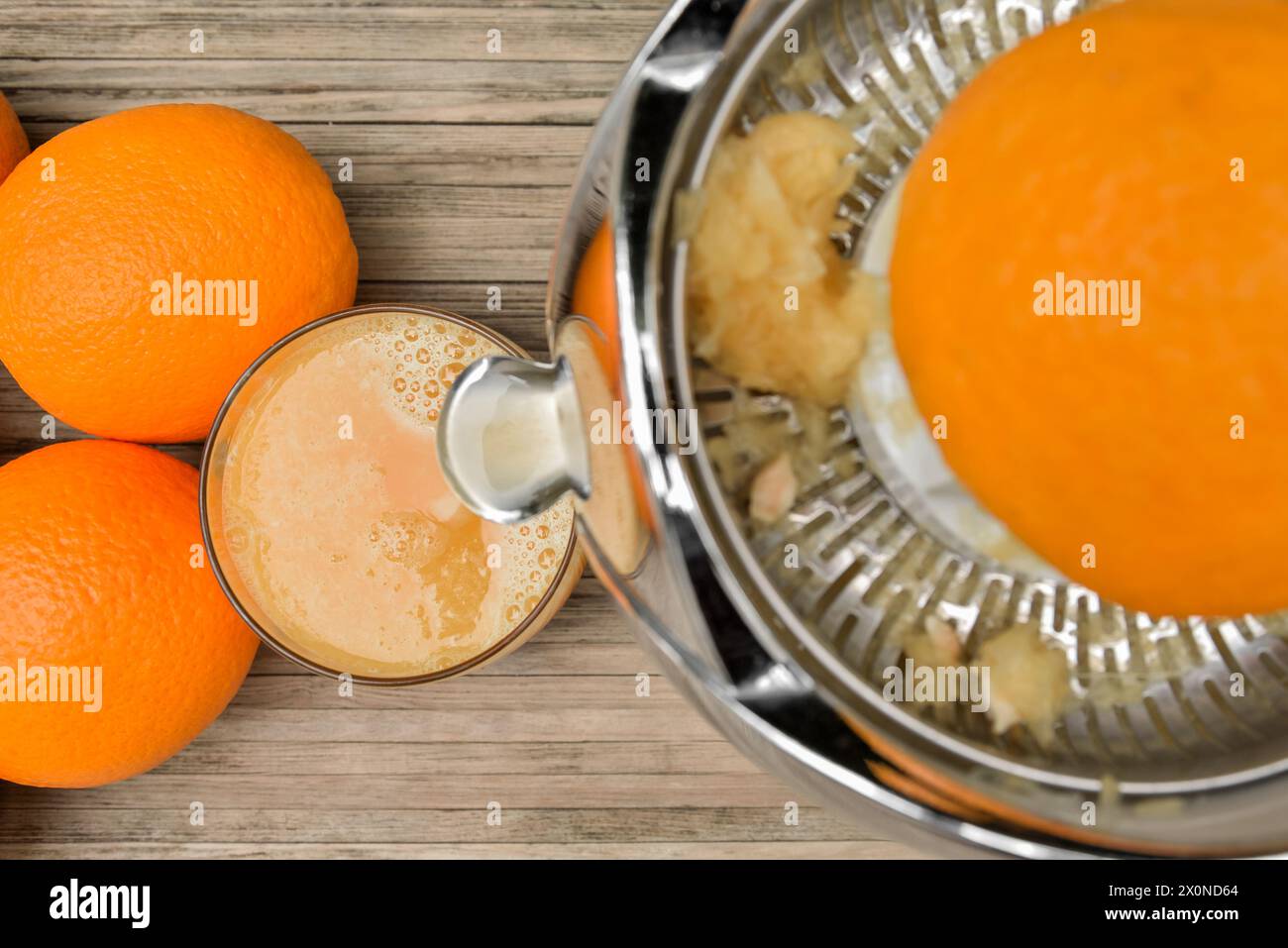 Blick von oben auf Glas mit Orangensaft beim Entsaften mit Zitruspresse Stockfoto