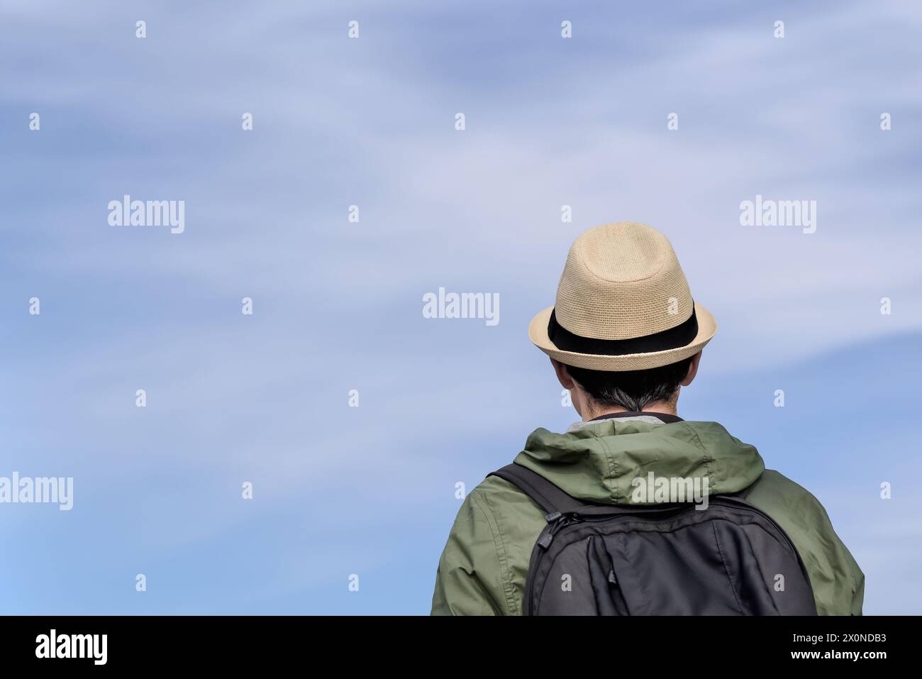 Rückansicht eines Reisenden mit Rucksack vor dem blauen Himmel. Touristen, Rucksacktouristen mit Hut schaut in den Himmel. Stockfoto
