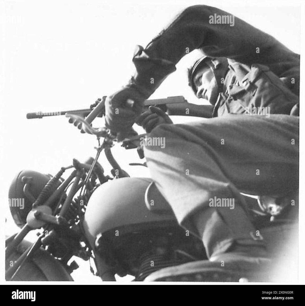 Ein Wachmann wird auf einem Motorrad fotografiert, das mit einer Tommy-Pistole ausgestattet ist und für militärische Transporte und Verteidigung verwendet wird. Stockfoto