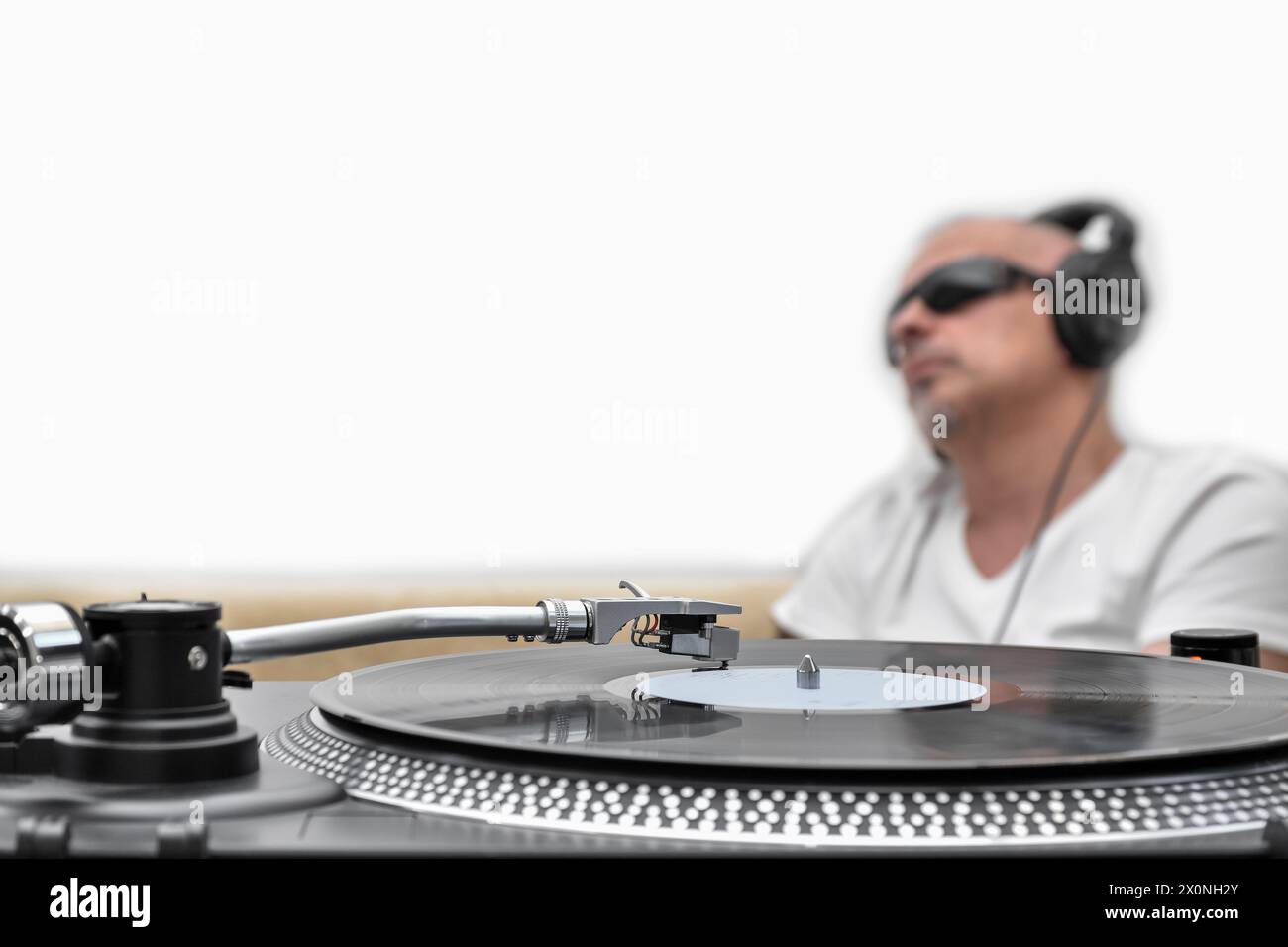Vinyl-Player, Plattenspieler auf dem Hintergrund eines verschwommenen Mannes in Kopfhörern, der Musik hört Stockfoto