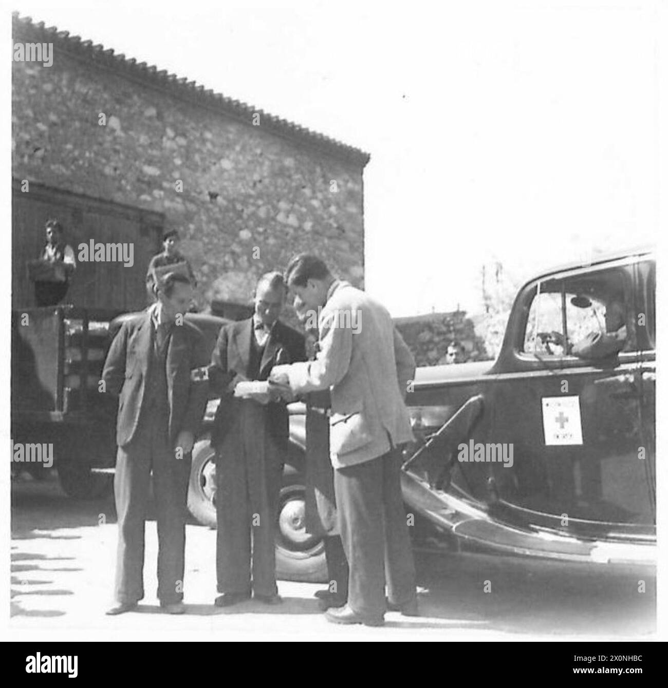 Ein fotografisches Negativbild, das Fred H. Mulder vom Schweizerischen Roten Kreuz zeigt, wie er mit einem griechischen Vorarbeiter und Lagerleiter eine Liste der Lebensmittellieferungen während der Verteilung von Lebensmitteln von Neuseeland nach Griechenland überprüft. Stockfoto