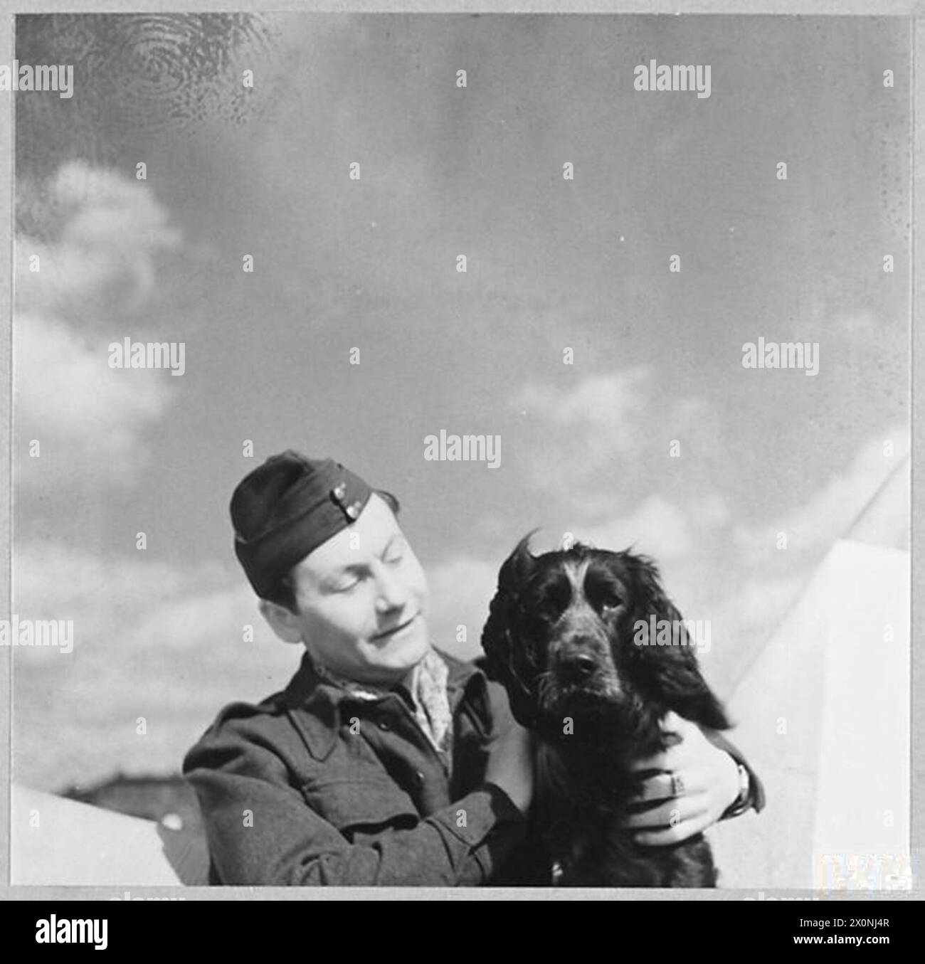 Foto eines Bodenmechanikers der polnischen Jagdgeschwader Nr. 303, der am 10. April 1942 mit einem Spaniel-Hund, dem Haustier eines Offiziers, bei der RAF Northolt spielte. Stockfoto