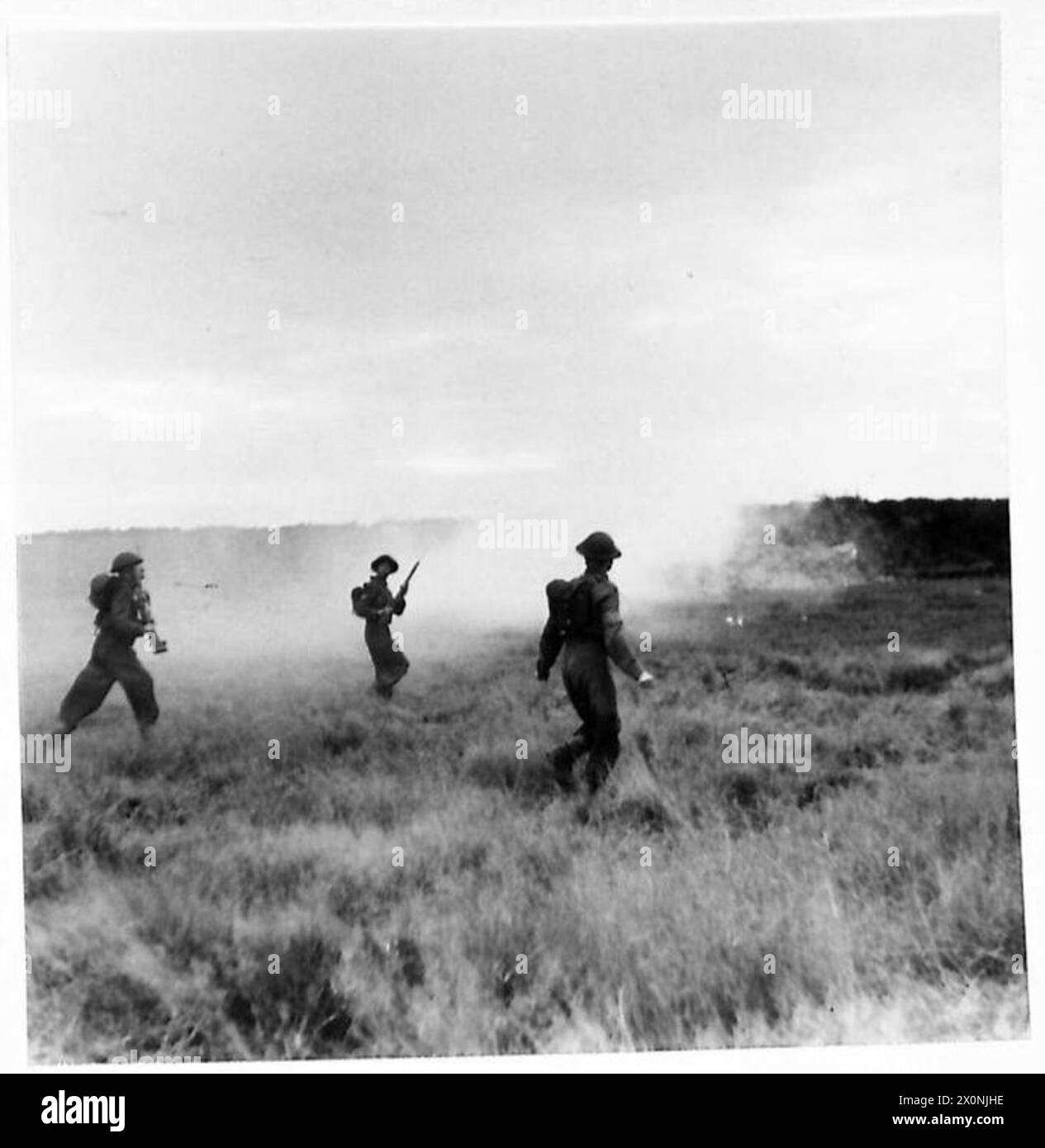 Angreifende Streitkräfte dringen durch einen Rauchschirm vor, während Kriegskorrespondenten die Kampfschule beobachten und dabei Training und Feldmanöver demonstrieren. Stockfoto