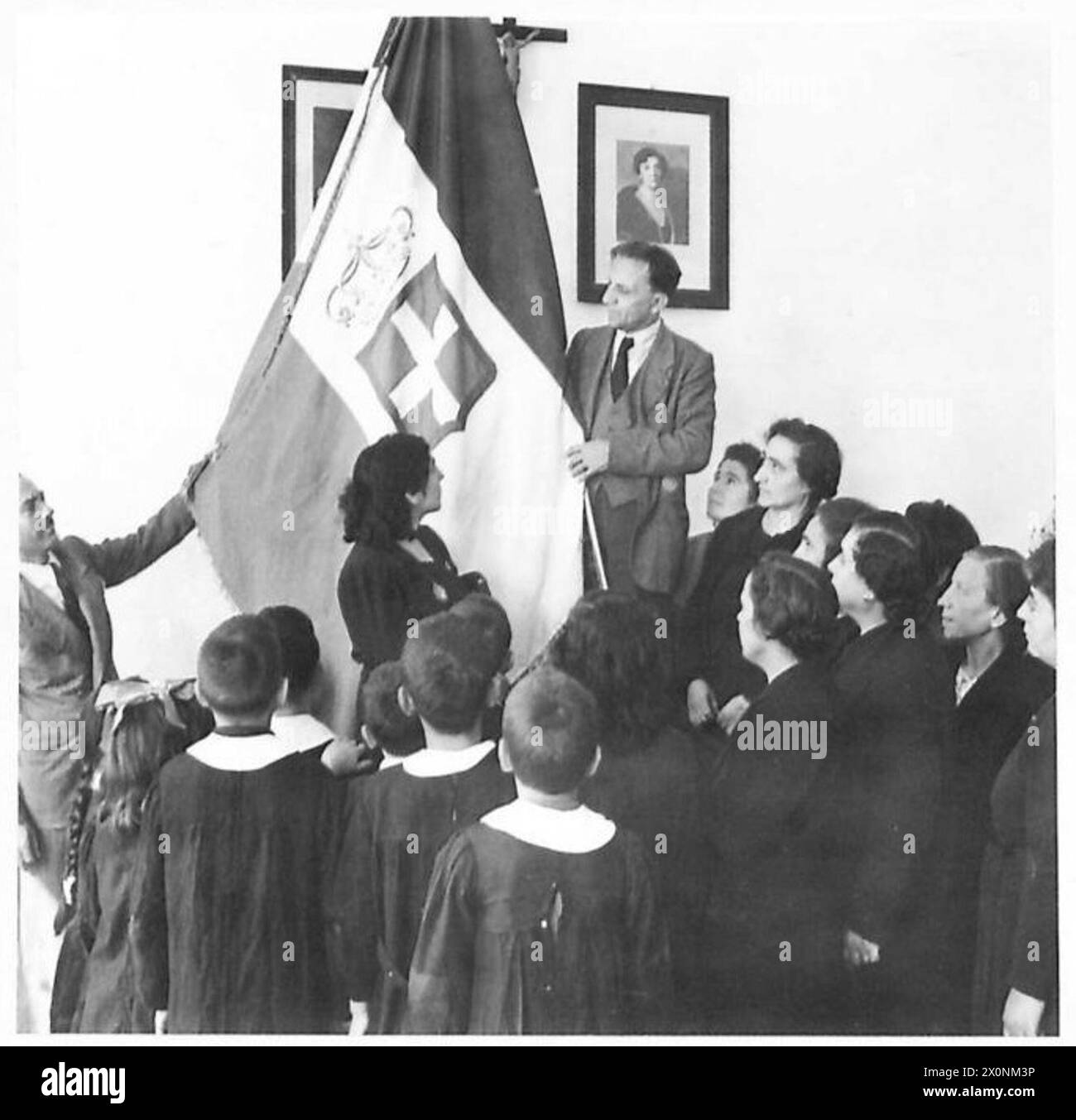 Kinder in den von den Alliierten besetzten italienischen Städten, darunter Apricena, nehmen nach drei Jahren wieder die Schule auf; Klassenzimmer haben faschistische Embleme und Porträts entfernt und durch das Porträt der Königin ersetzt, und Uniformen werden nicht mehr getragen. Stockfoto