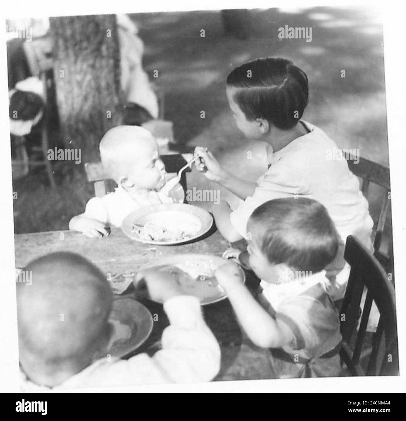 UNRRA-ESSEN FÜR WAISENKINDER: Die Schwestern im Warenhaus servieren den Kindern ein Open-Air-Frühstück. Das Frühstück besteht aus Brot und Milchmahlzeit. Fotografisches negativ, britische Armee Stockfoto