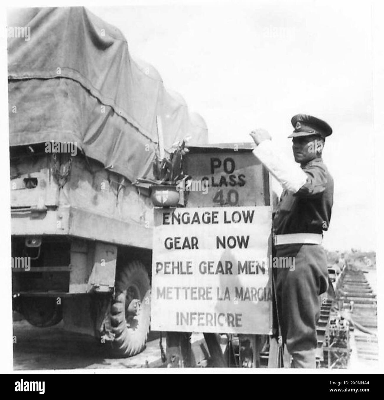 Ein Militärpolizist, L/CPL H. Bylett von 101 Provost Coy., steht neben einem dreisprachigen Schild am Ende der Bailey Pontonbrücke über den Po River. Stockfoto