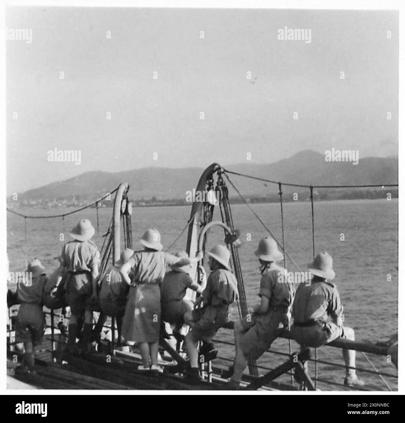 Truppenschiffe in einem Konvoi in den Nahen Osten säumen die Decks und beobachten den ersten Anblick von Land nach einer Seereise. Stockfoto
