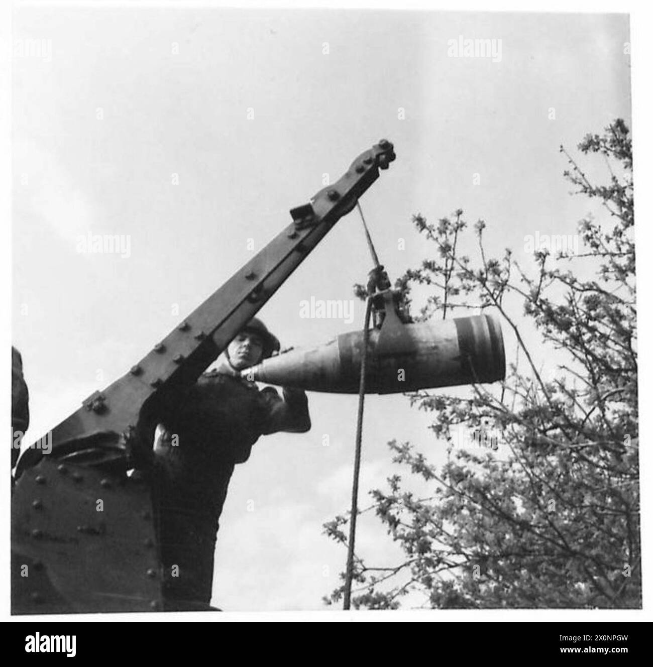 Eine Granate wird auf eine Laderiege gehoben, die den Umgang mit Artillerie und Kampfhandlungen im militärischen Kontext veranschaulicht. Stockfoto