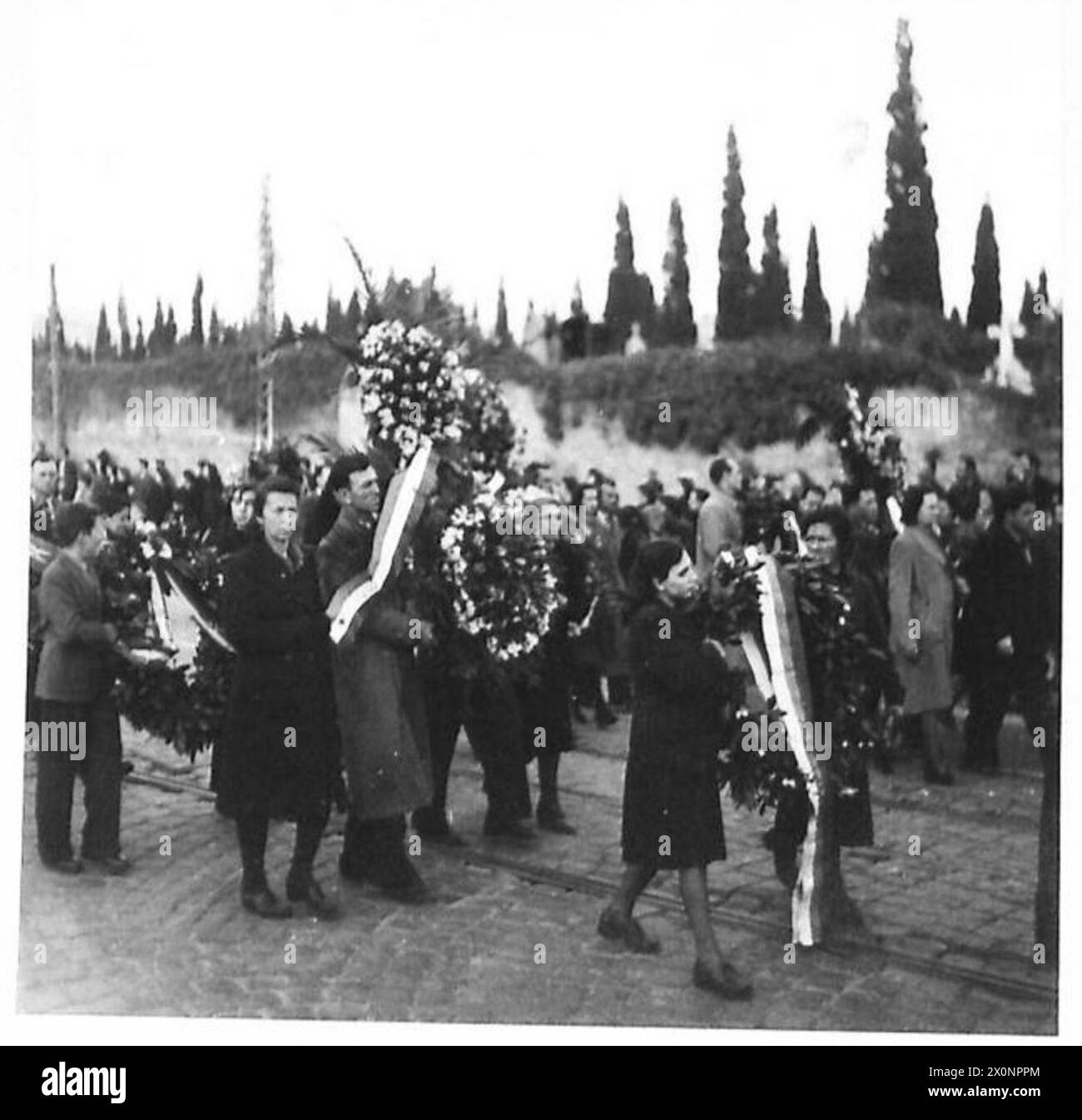 Kränze werden während der Trauerprozession für die Opfer der Servola-Erschießungen in Triest getragen. Stockfoto