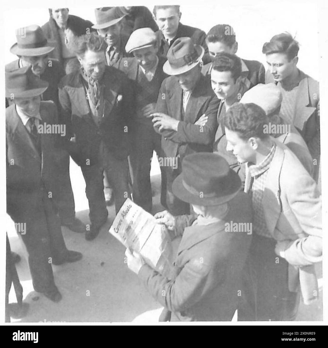 Die Einwohner einer italienischen Stadt lesen eine der wenigen Zeitungen, die in der Gegend ankommen. Stockfoto