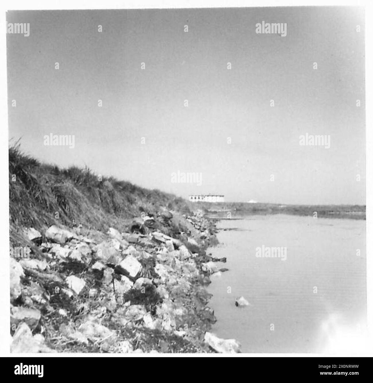 Kommandos der Achten Armee rücken entlang einer Deichmauer in Richtung eines von Deutschland gehaltenen Kraftwerks vor, wobei Verluste durch schwere Maschinengewehre und Mörserfeuer sichtbar sind. Stockfoto