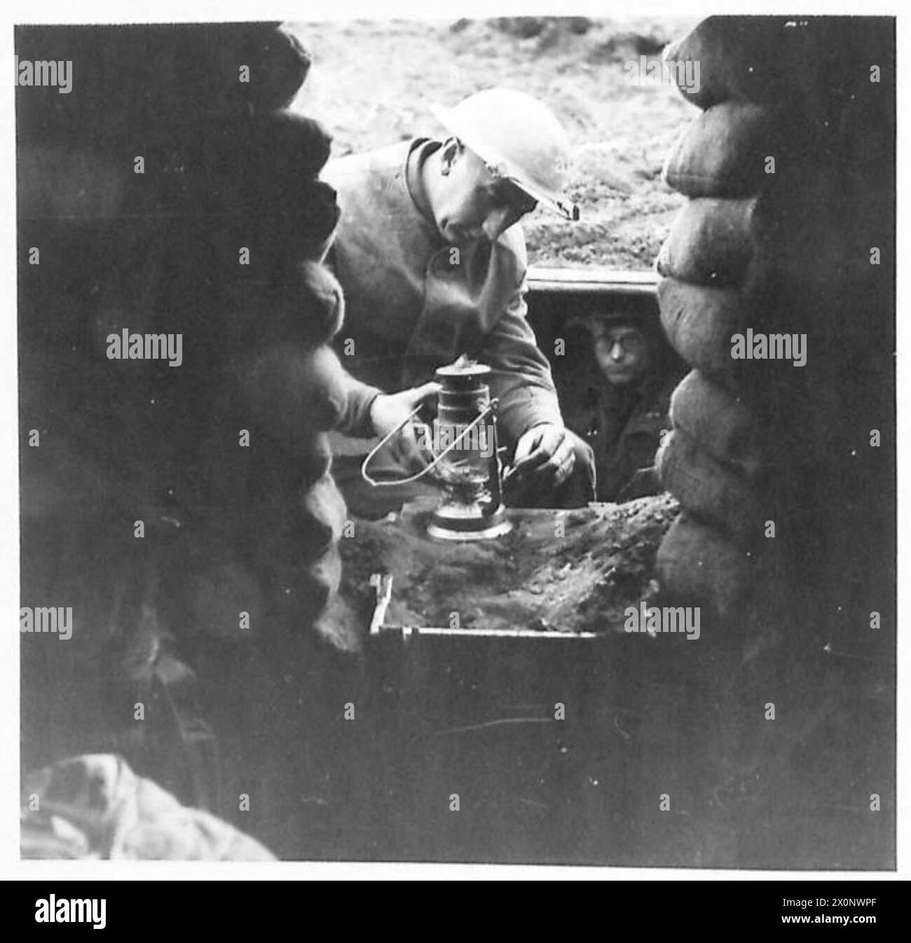 Sgt. H. French von der Film- und Fotoeinheit Nr. 2 der Armee zündet eine Öllampe in seiner Ausgrabung am Anzio-Brückenkopf an; Ausgrabungen bieten besseren Schutz für die Truppen. Fotografisches negativ der britischen Armee. Stockfoto