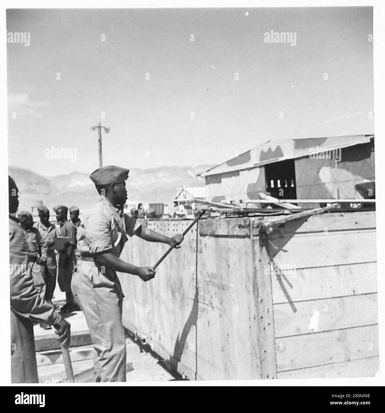 Fotografisches negativ, das Basutos aus Südafrika zeigt, die im Pioneer Corps dienten und Kisten von kanadischen LKWs zerbrachen, die während der Operationen der britischen Armee im Nahen Osten ankommen. Stockfoto
