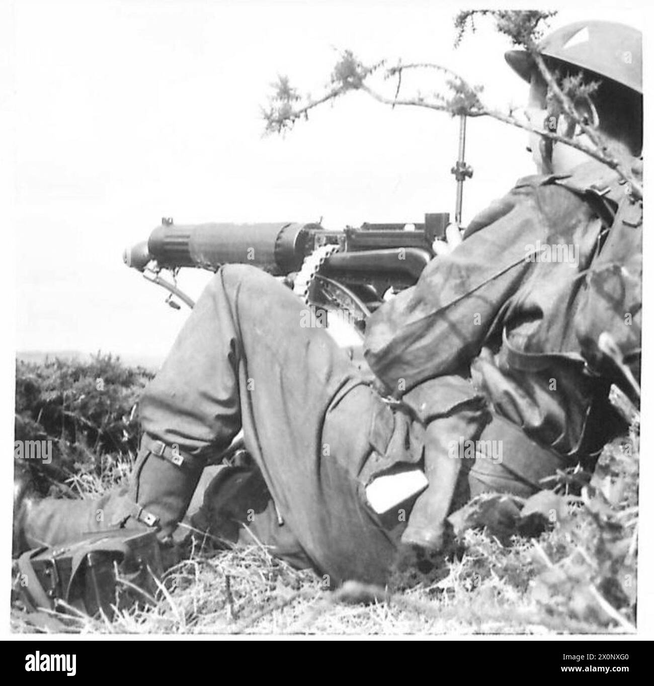 Ein Infanterie-Maschinenschützer wird an seinem Posten gezeigt, der während einer Übung einen Angriff anführt. Ein fotografisches negativ dokumentiert die Operation. Stockfoto