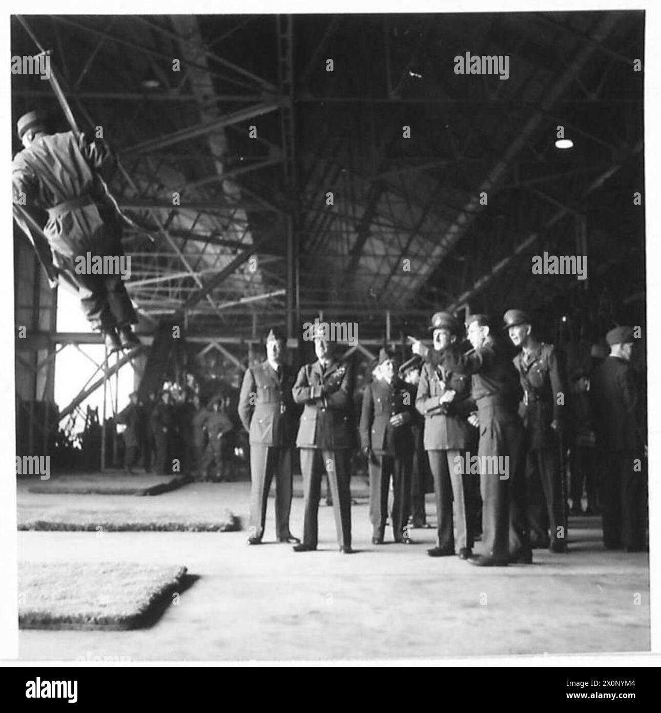 Kommandanten der Armee und der Luftwaffe beobachten das Fallschirmjäger-Training, während ein Geschwaderführer die Methode des Swing-Trainings erklärt. Stockfoto