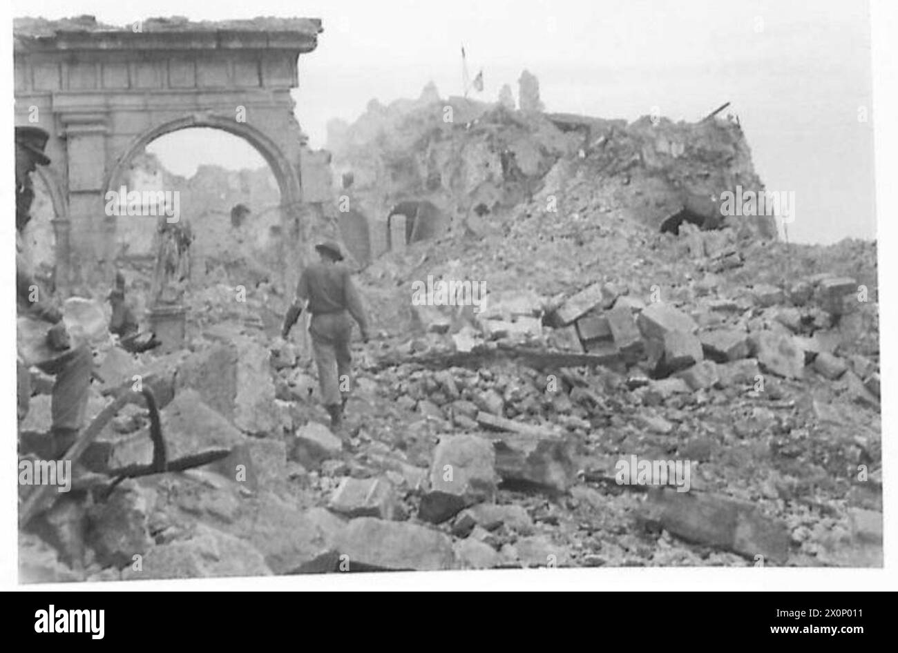 DIE SCHLACHTEN VON MONTE CASSINO, JANUAR-MAI 1944 - Ein Soldat der 2. Brigade, 3. Karpaten-Gewehre-Division (2. Polnisches Korps), der 19. Mai 1944 durch den Ruinenhof der Abtei Monte Cassino geht. Beachten Sie die beschädigte Statue des Heiligen Benedikt, des Gründers der Abtei, auf der linken Seite. Polnische und britische Fahnen, die über den Überresten des Turms gehisst werden, sind im Hintergrund zu sehen britische Armee, polnische Armee, polnische Streitkräfte im Westen, polnische Streitkräfte im Westen, polnische Streitkräfte im Westen, polnische Streitkräfte im Westen, Karpaten-Gewehre Divisior, 3, polnische Streitkräfte im Westen, 2. Korps, 3. Karpaten-Gewehre-Division, 2 Stockfoto