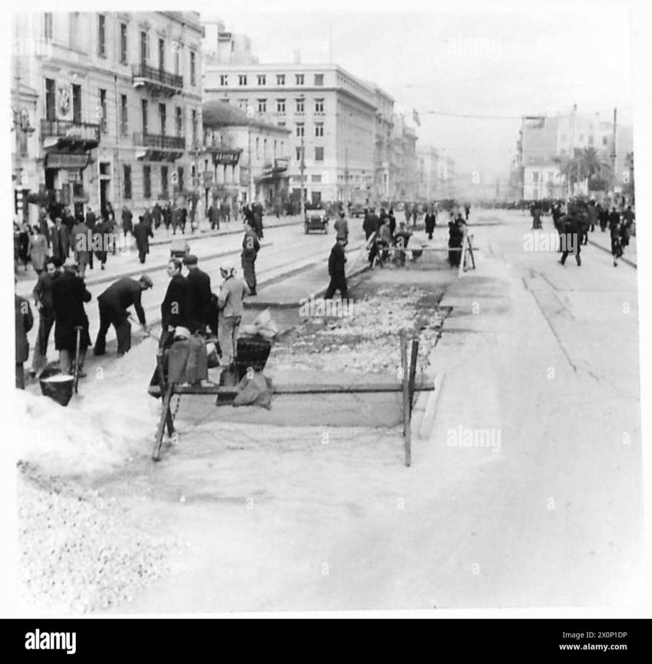 "DAS LEBEN KEHRT WIEDER NACH ATHEN ZURÜCK" - Ein Abschnitt der Straße in der Universitätsstraße, die eines der wichtigsten Einkaufszentren Athens ist, hat stark unter Waffenfeuern gelitten. und durch den konstanten Strom von Panzern, die über sie hinübergegangen sind, wird gesehen, wie Griechen mit Hilfe einiger britischer Tommäen repariert wurden. Fotografisches negativ, britische Armee Stockfoto