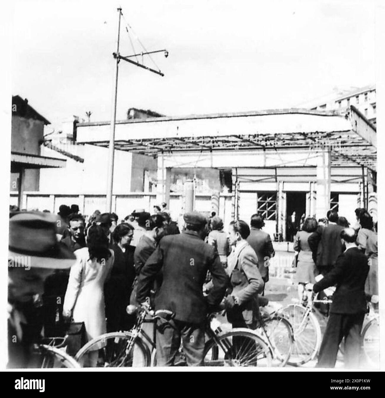 Die Leichen von Mussolini und seinen Mitarbeitern wurden am 29. April an einer Mailänder Tankstelle aufgehängt. Einheimische beobachten aus der Umgebung. Fotografiert von der britischen Armee. Stockfoto