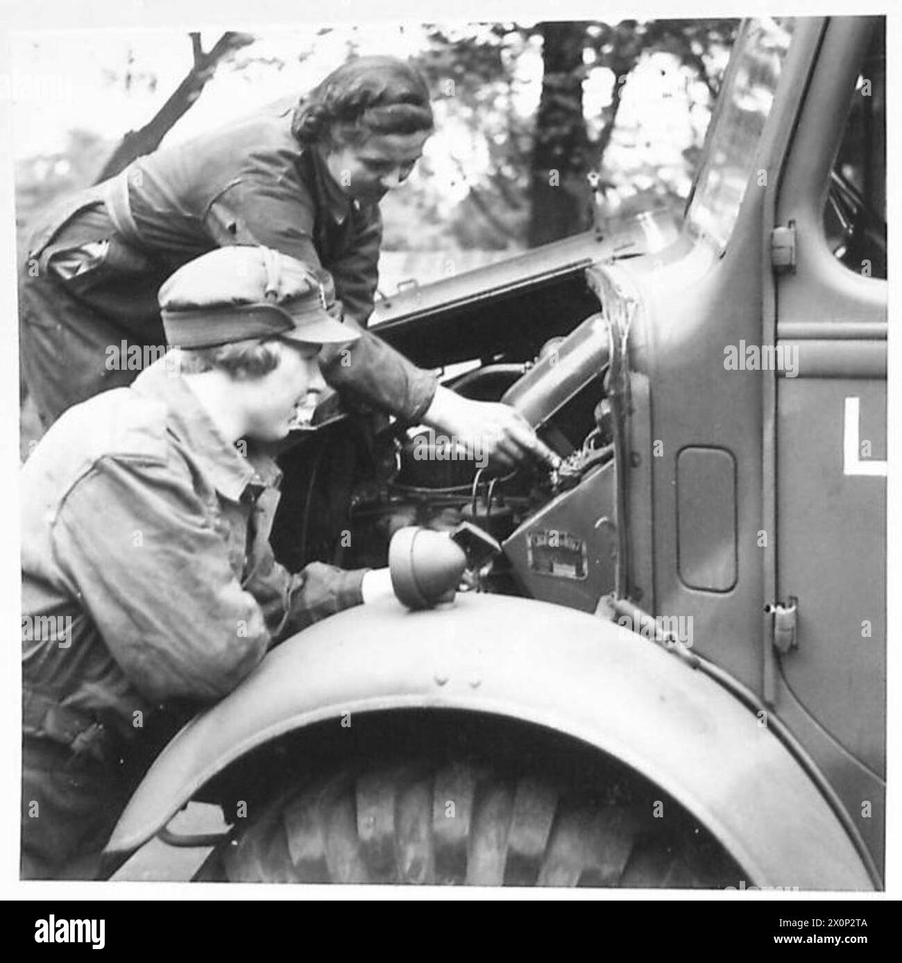 Weibliche Soldaten führen Inspektionen und Wartungsarbeiten durch und stellen einen Lkw-Motor im Rahmen der britischen Armee ein. Stockfoto
