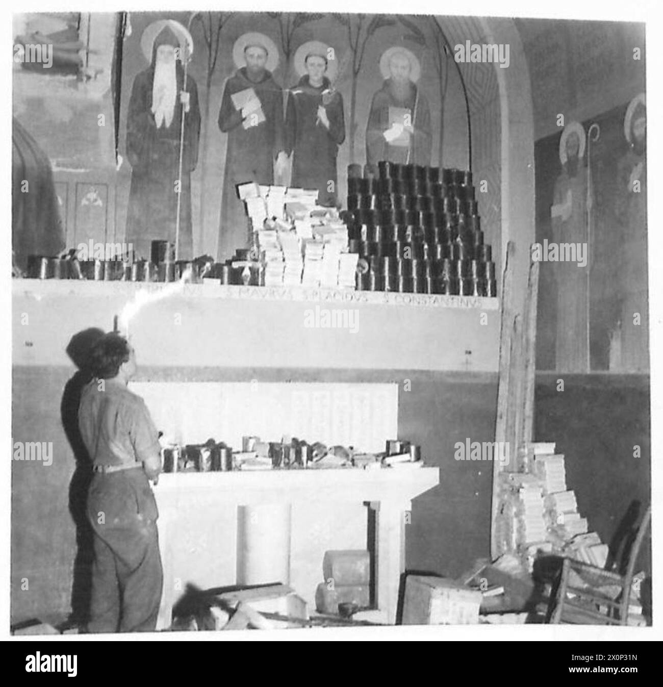 Ein Soldat der 2. Brigade, 3. Karpaten-Gewehre-Division, 2. Polnisches Korps, inspiziert am 19. Mai 1944 während der Schlacht von Monte Cassino auf dem Altar der Kathedrale von Monte Cassino gelagerte deutsche Konserven und Munition. Stockfoto
