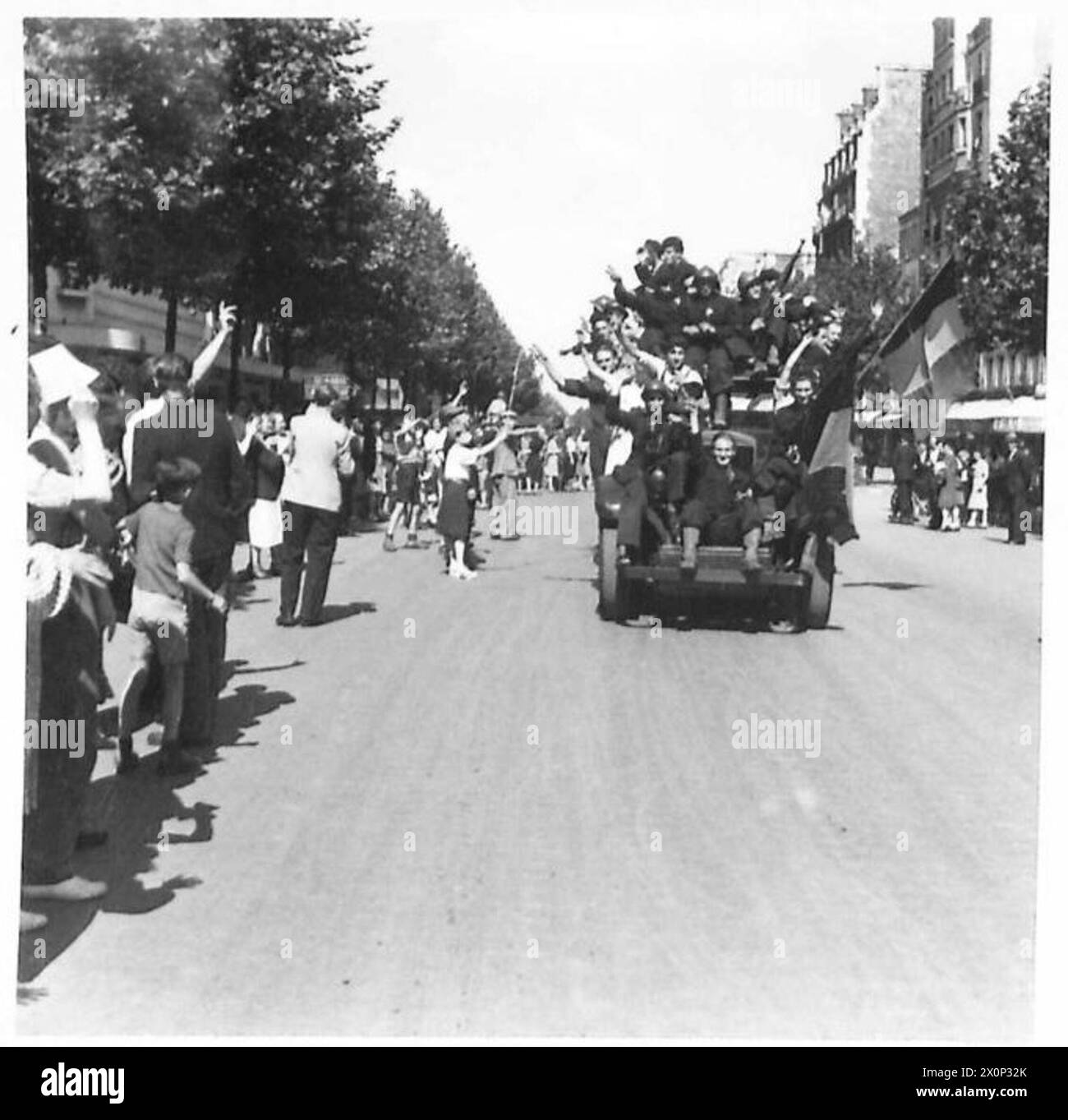 Die Menschen von Paris säumen die Straßen, um britische, amerikanische, kanadische und französische Truppen zu begrüßen, die 1944 in die befreite Stadt einmarschieren. Stockfoto