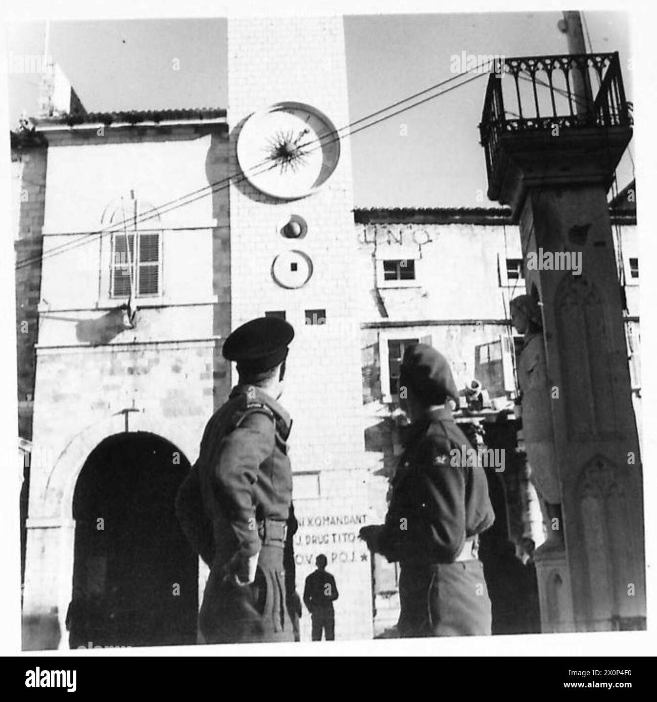 Eine Stadtuhr in Jugoslawien zeigt die Uhrzeit mit numerischen Zeitfenstern an, die nachts hinterleuchtet werden. Fotografisches negativ dokumentiert die lokale Infrastruktur während der Operationen der britischen Armee. Stockfoto