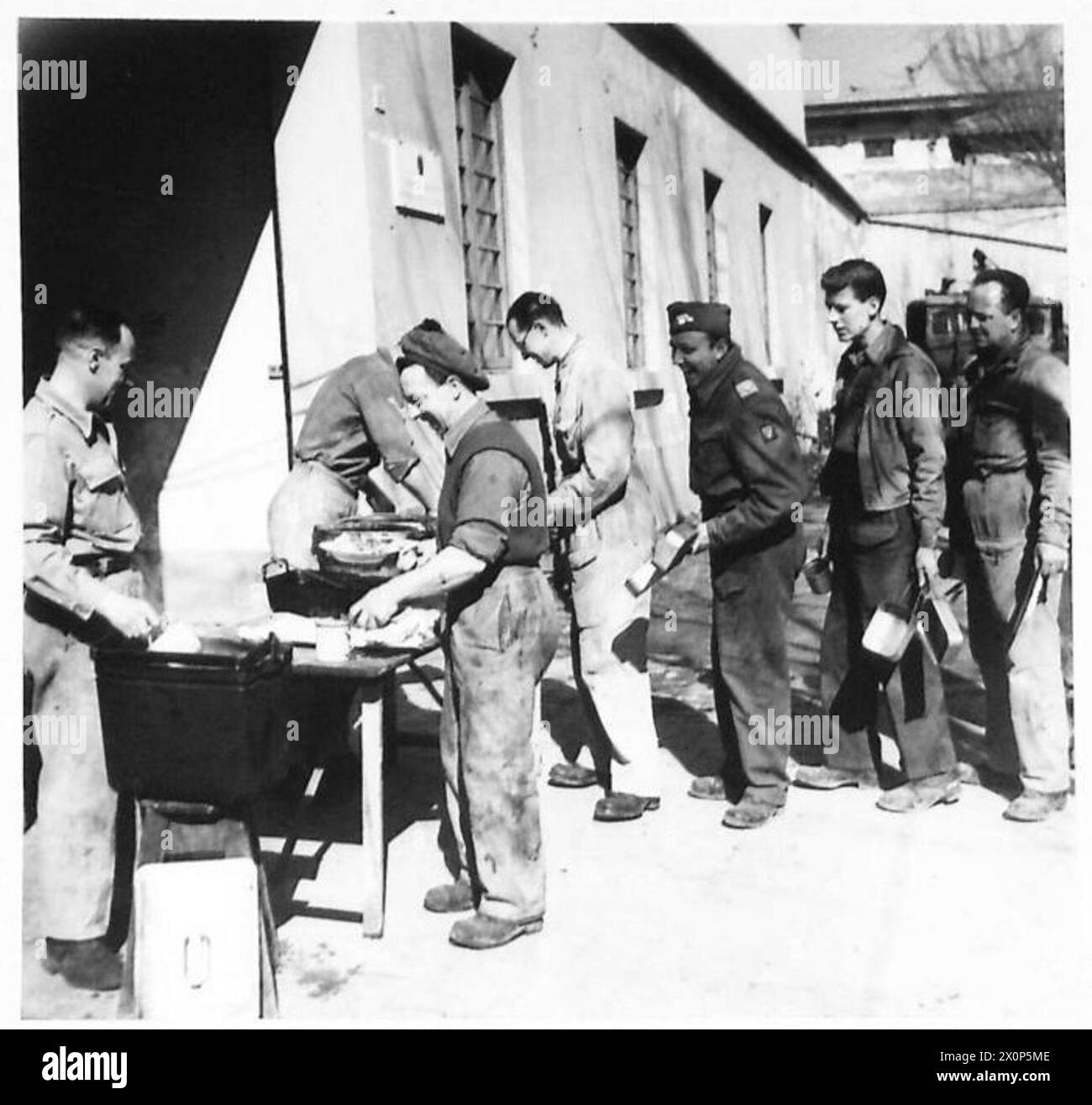 AMERIKANISCHER FELDDIENST MIT DER ACHTEN ARMEE - britische Soldaten und amerikanische Freiwillige Ambulanzfahrer stellen sich für ihr Mittagessen an, das von einem britischen Koch serviert wird. Fotografisches negativ, britische Armee Stockfoto