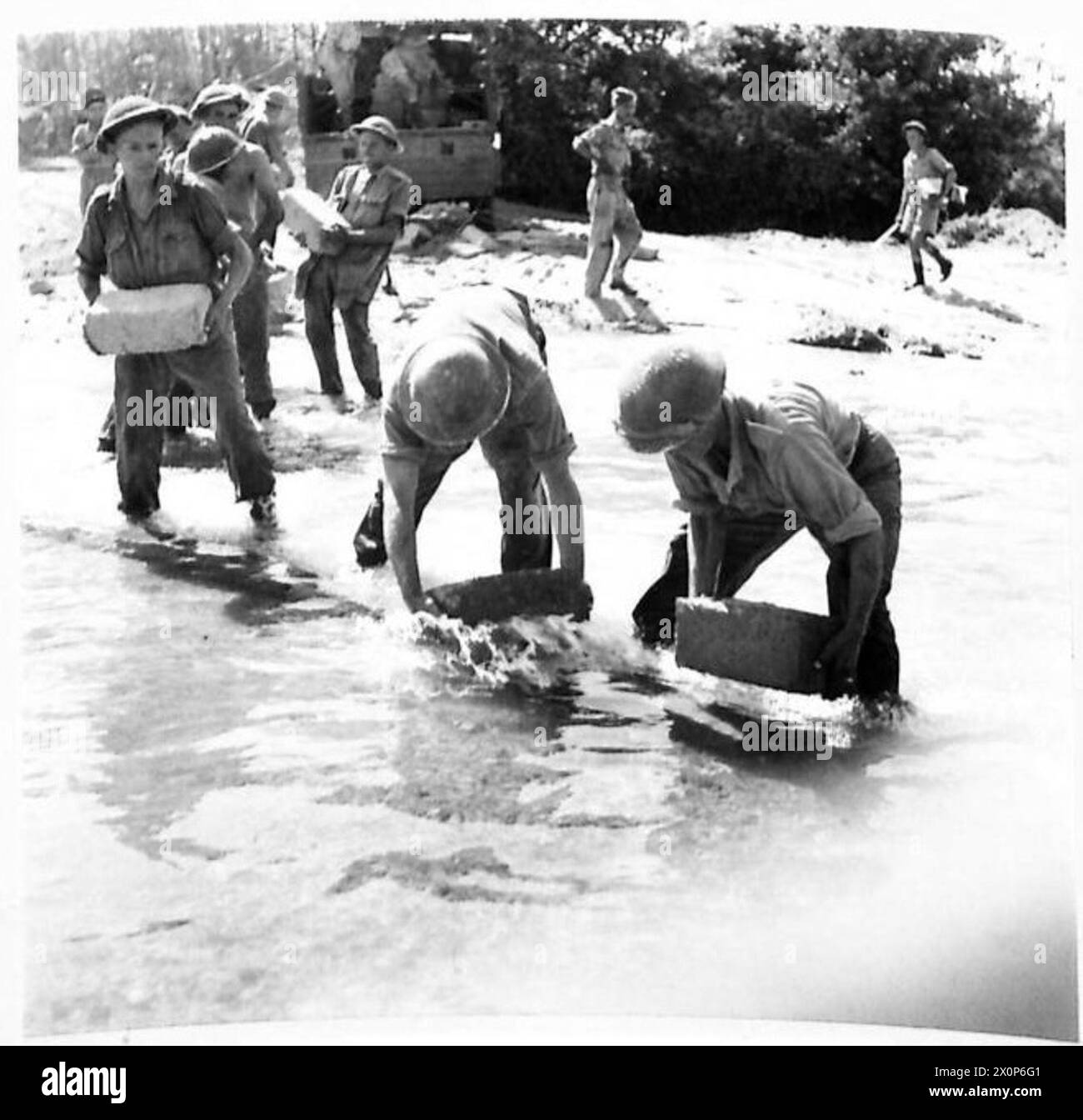 Die Ingenieure bauen einen Staudamm auf halbem Weg mit Lastkraftwagen aus Ziegelsteinen, um während der Invasion Italiens Wasser aus einem schlammigen Gebiet abzuleiten. Fotografisches negativ, britische Armee. Stockfoto
