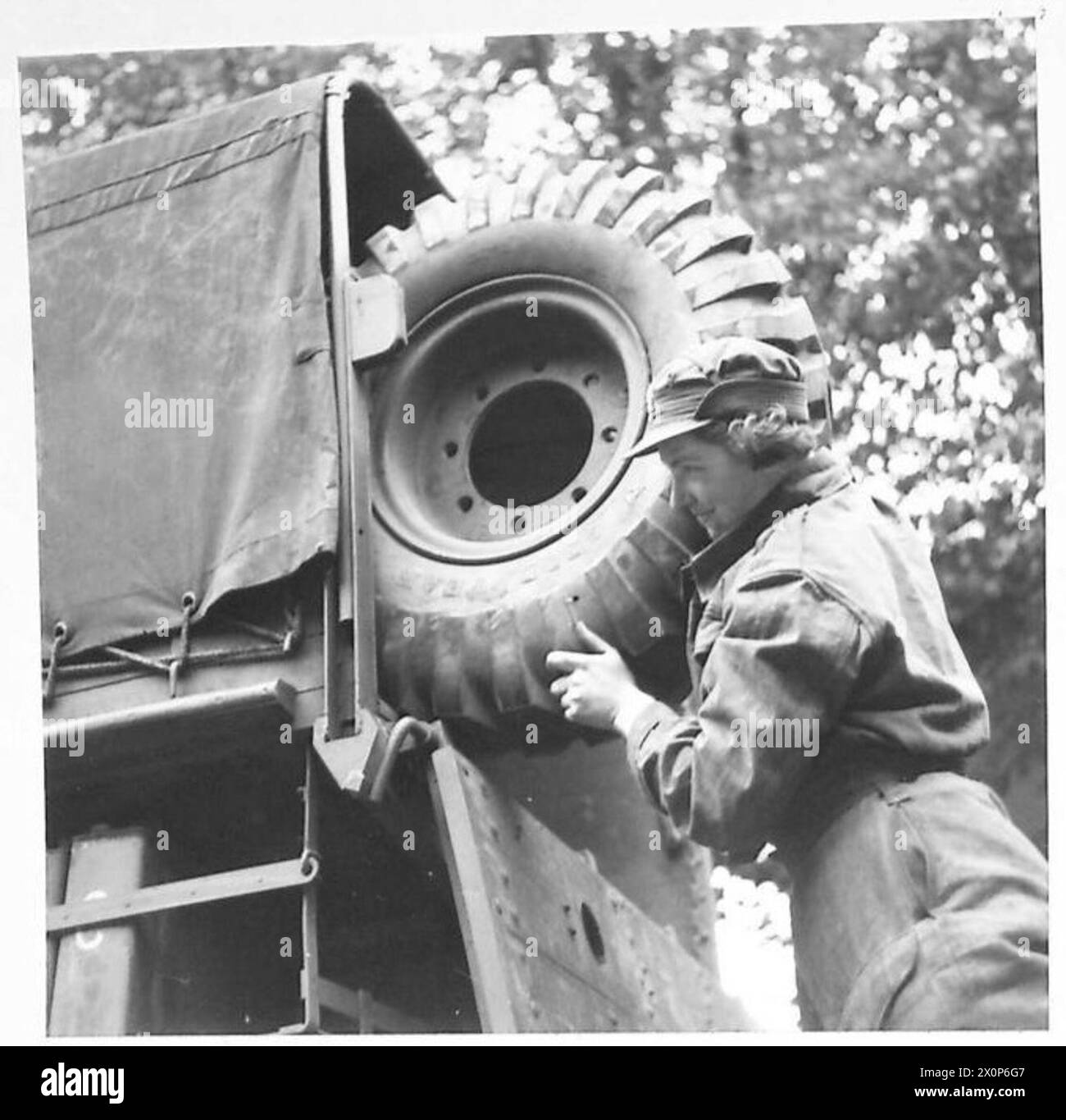 Soldatinnen heben ein Reserverad in einen LKW und erfüllen körperlich anspruchsvolle Aufgaben, die normalerweise Männern zugewiesen werden. Stockfoto