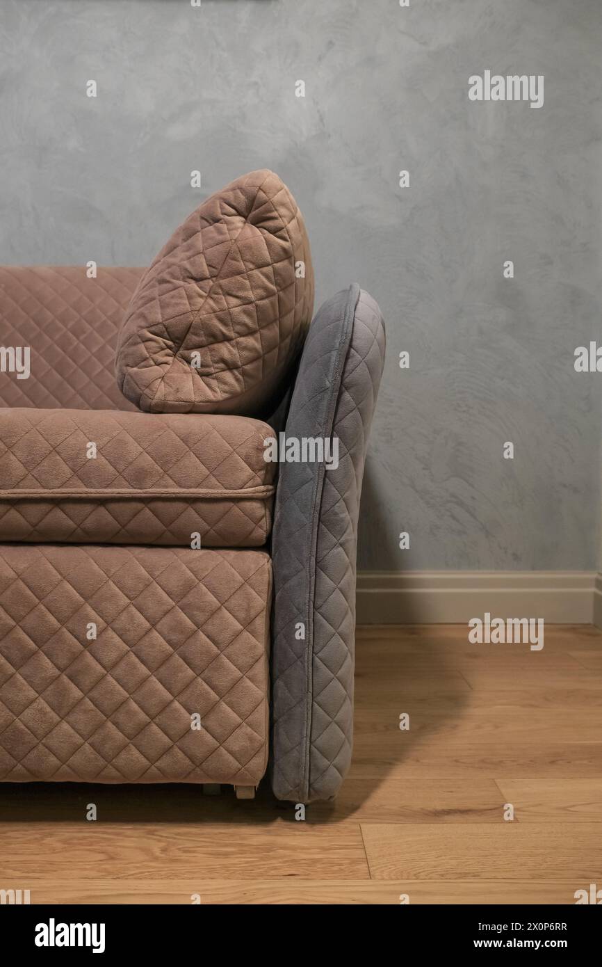 Teil eines modernen beigefarbenen Sofas vor einer grauen Wand im Wohnzimmer Stockfoto
