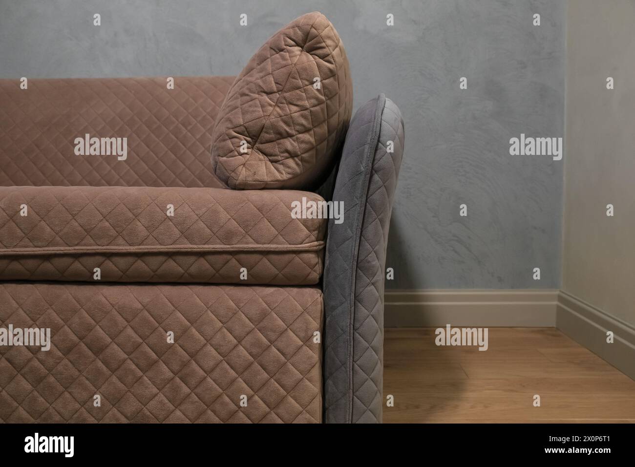 Modernes beigefarbenes Sofa vor einer grauen Wand im Wohnzimmer Stockfoto