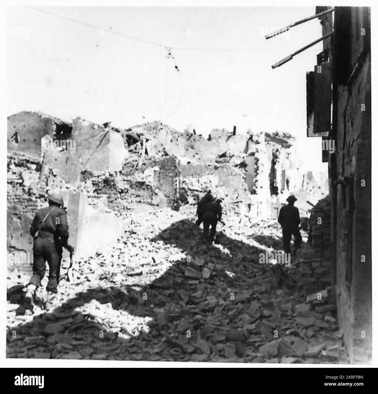 Infanteristen der 4. Kompanie, 1. East Surreys, ziehen unter dem Schutz von Bren-Kanonen durch Cotignola vor; die Stadt leidet unter Bomben und Schießereien. Stockfoto