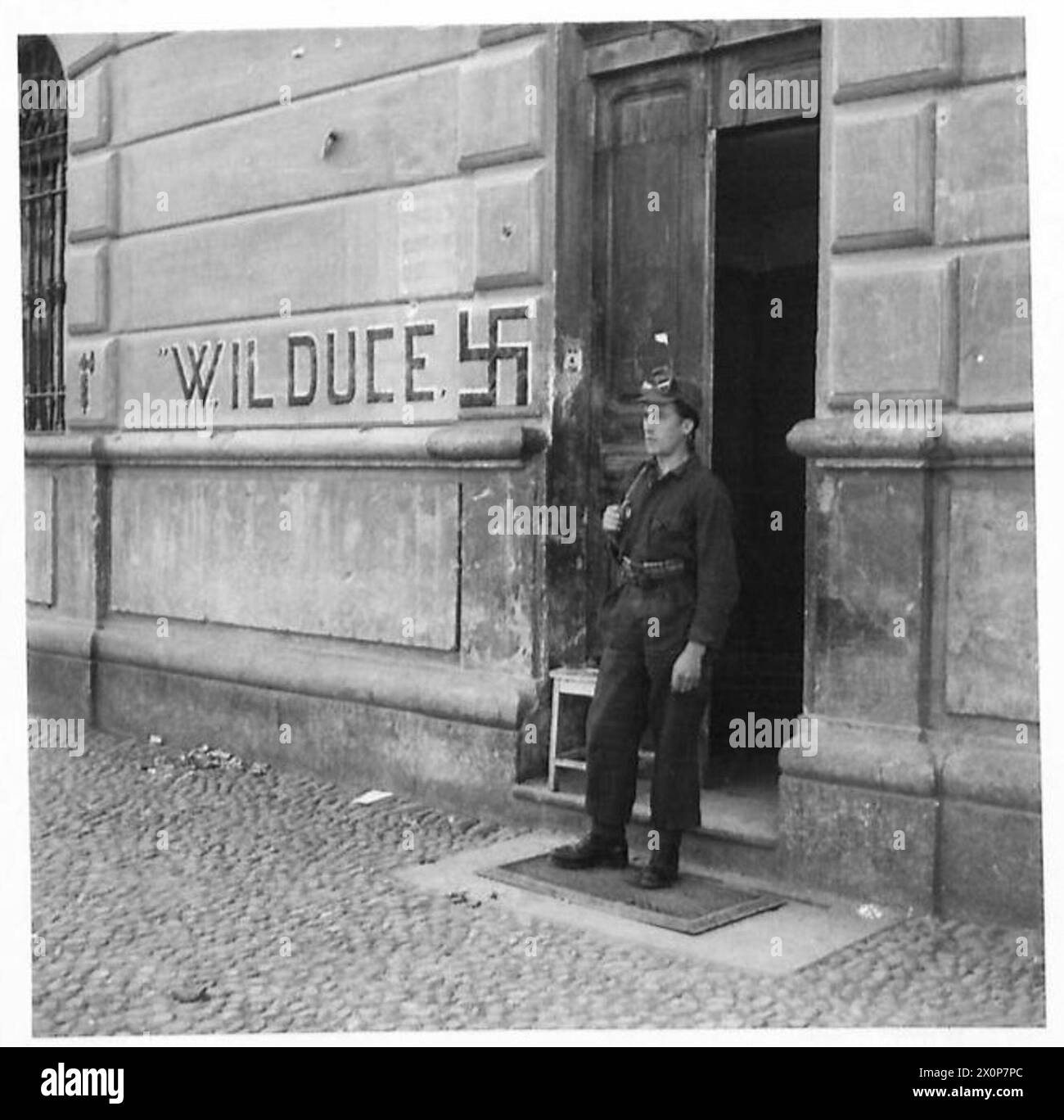 Ein Partisanen bewacht das ehemalige faschistische Hauptquartier in Cuneo, Italien, nahe der französischen Grenze, nachdem die Faschisten aus der Stadt geflohen waren. Stockfoto