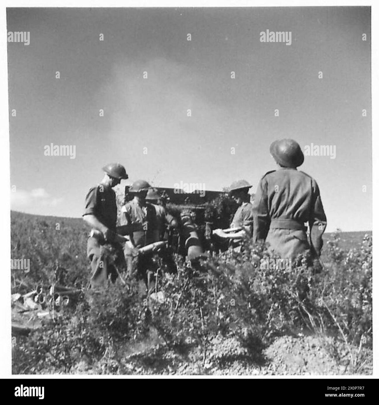 25-Pfünder-Artilleriegeschosse schießen auf die tunesische Front, wobei Soldaten die Geschützpositionen bedienen. Stockfoto