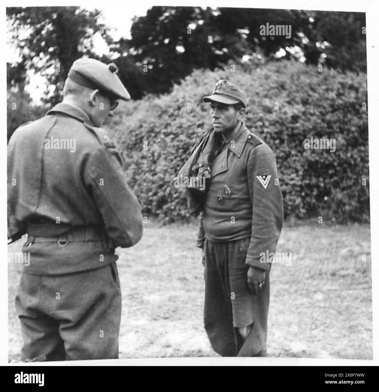 Ein deutscher Soldat wird von britischen Armeeangehörigen der 21. Armeegruppe in der Normandie verhört. Das Foto zeigt den Moment der Befragung nach der Erfassung und spiegelt die Bemühungen wider, Informationen während der Normandie-Kampagne 1944 zu sammeln. Stockfoto