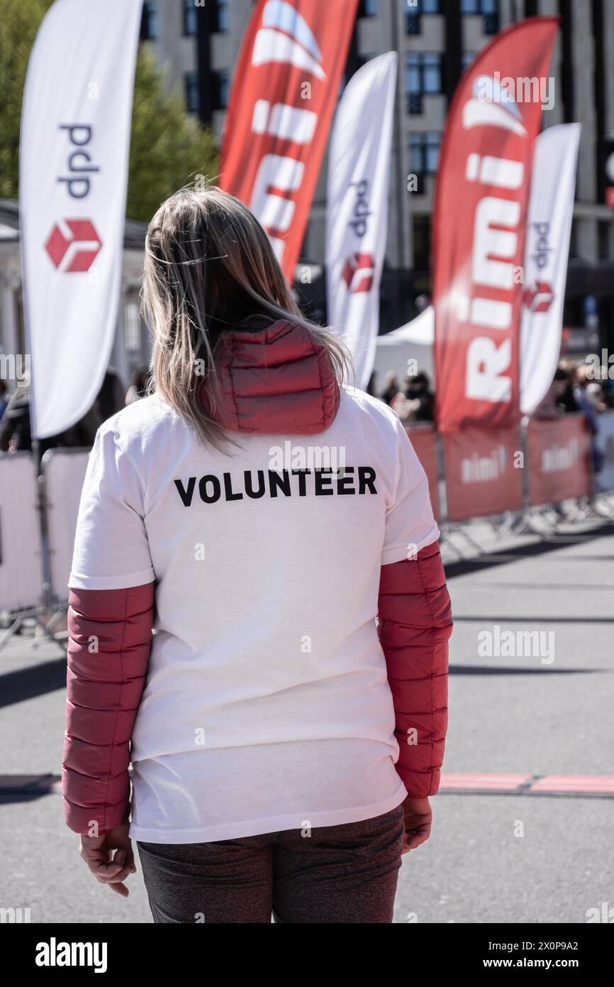 Rückansicht einer Frau mit der Inschrift Freiwillige bei einem öffentlichen Sportwettbewerb Rimi Riga Marathon: RIGA, LETTLAND - 5. Mai 2023 Stockfoto