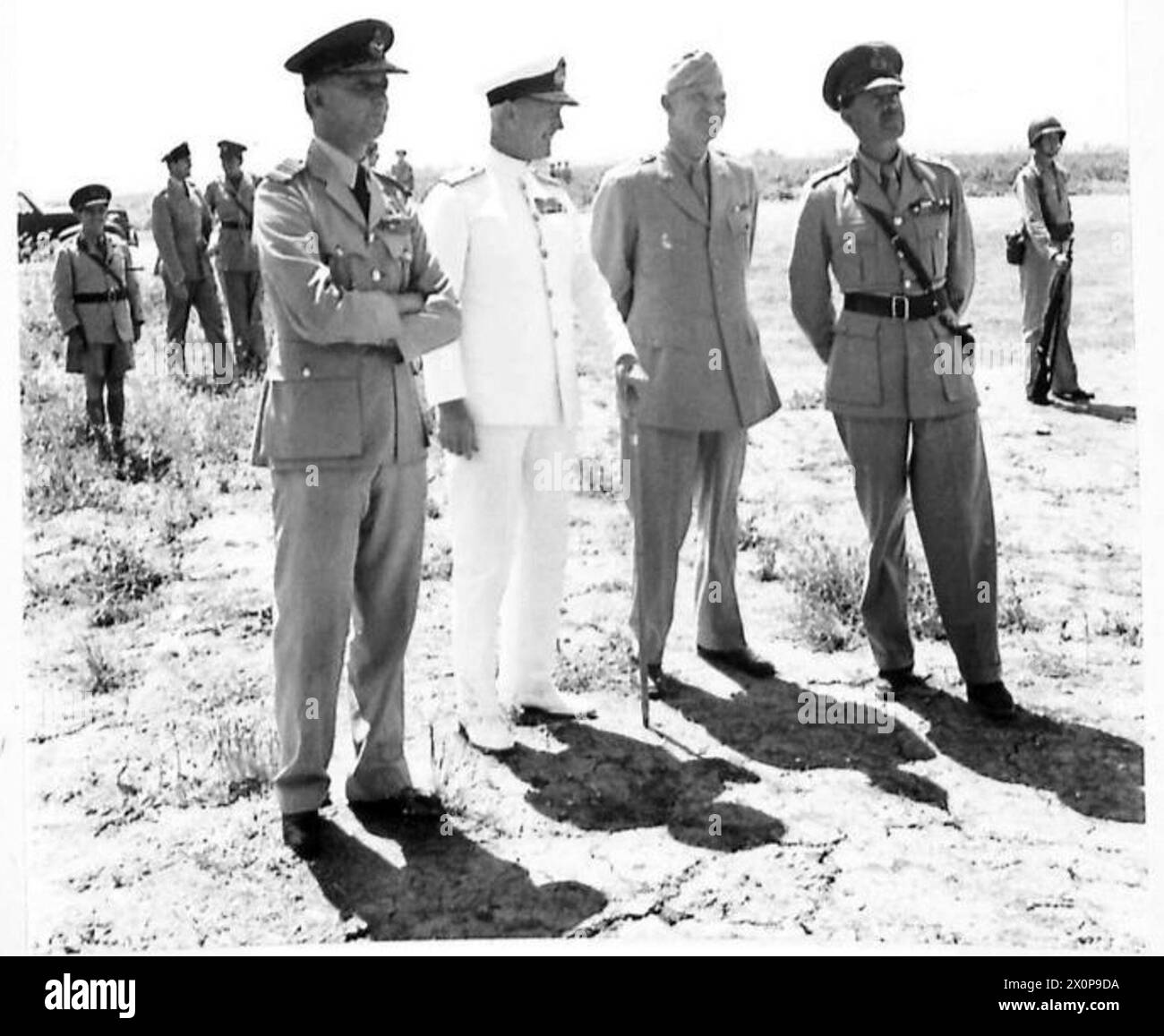 H.M. der König und hochrangige Militärs, darunter Air Marshal Tedder, Admiral Cunningham, General Eisenhower und General Alexander, warten auf ein Flugzeug, das während des Abflugs aus Nordafrika mit dem Taxi abfährt. Stockfoto