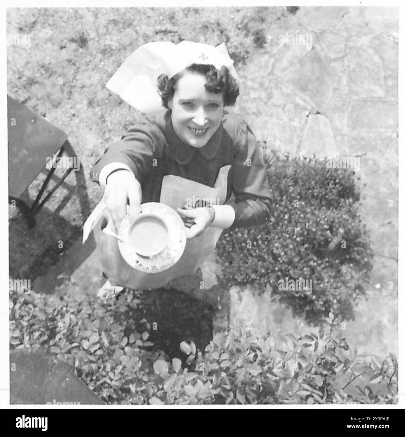 DAS BRITISCHE ROTE KREUZ UND ST. JOHN-KRIEGSORGANISATION - der Kommandant überreicht einem der Patienten eine Tasse Tee. Fotografisches negativ, britische Armee Stockfoto