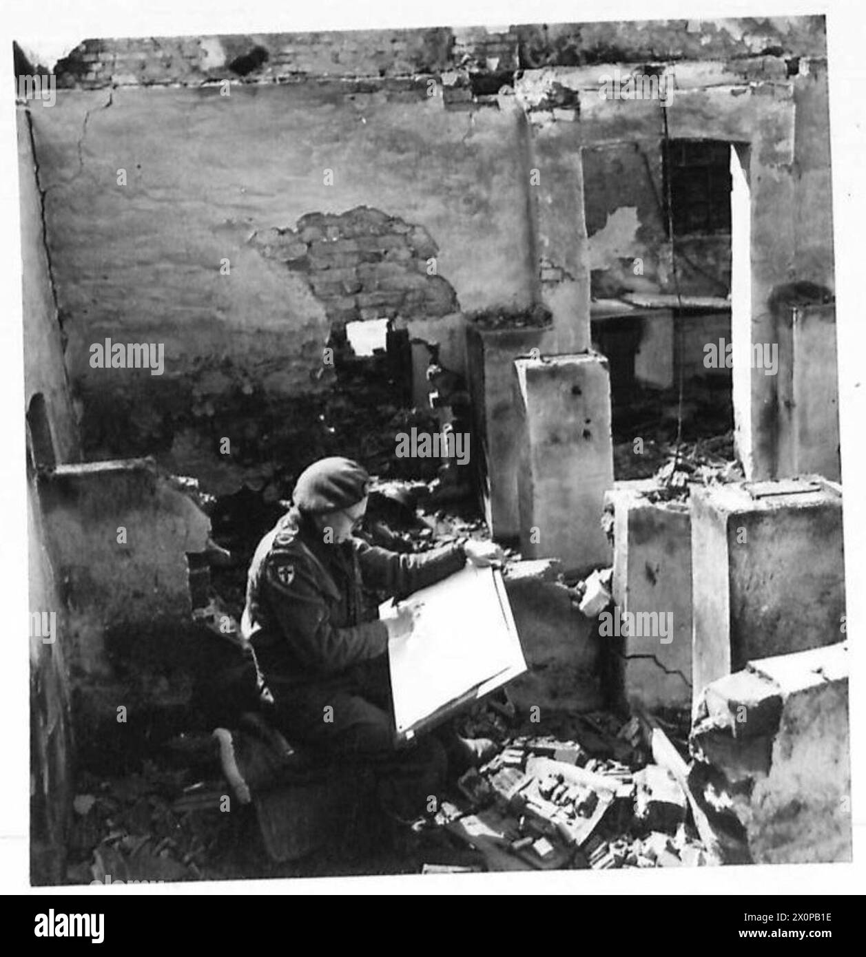 GILES IN DEUTSCHLAND – Er sitzt zwischen den Ruinen eines deutschen Bauernhofs und macht einen Hintergrund für einen seiner Zeichentrickfilme. Fotografisches negativ, britische Armee, 21. Armeegruppe Stockfoto