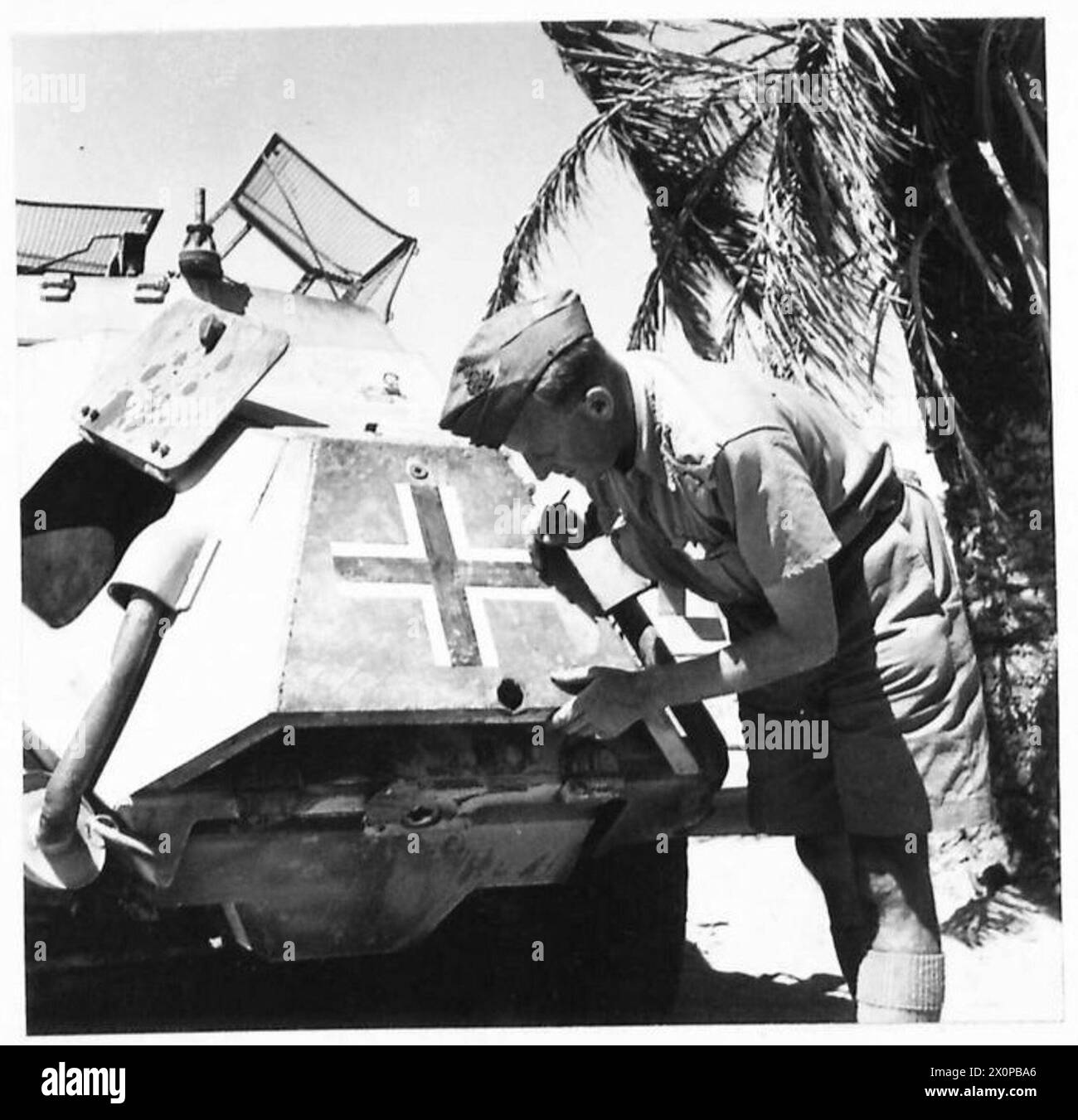 Foto eines gefangenen deutschen Panzerwagens mit einem Einschussloch, das in den Motor eindrang und ihn beschädigte, beobachtet von einem britischen Offizier. Stockfoto