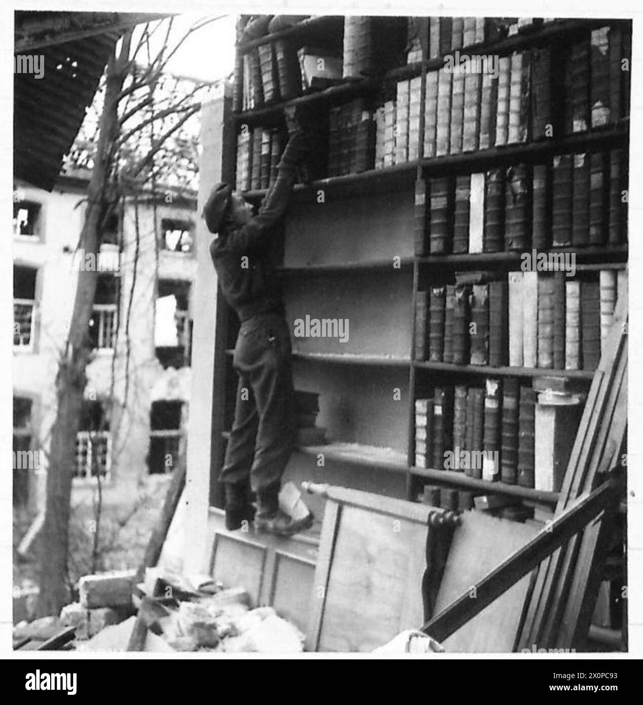 Der Anführer der Geschwader Dixon-Spain und der Privatmann John Burtoft von der britischen Armee bergen Bücher und Manuskripte aus beschädigten Bibliotheken in der Kathedrale von Xanton, während sie unter Granatfeuer stehen. Stockfoto