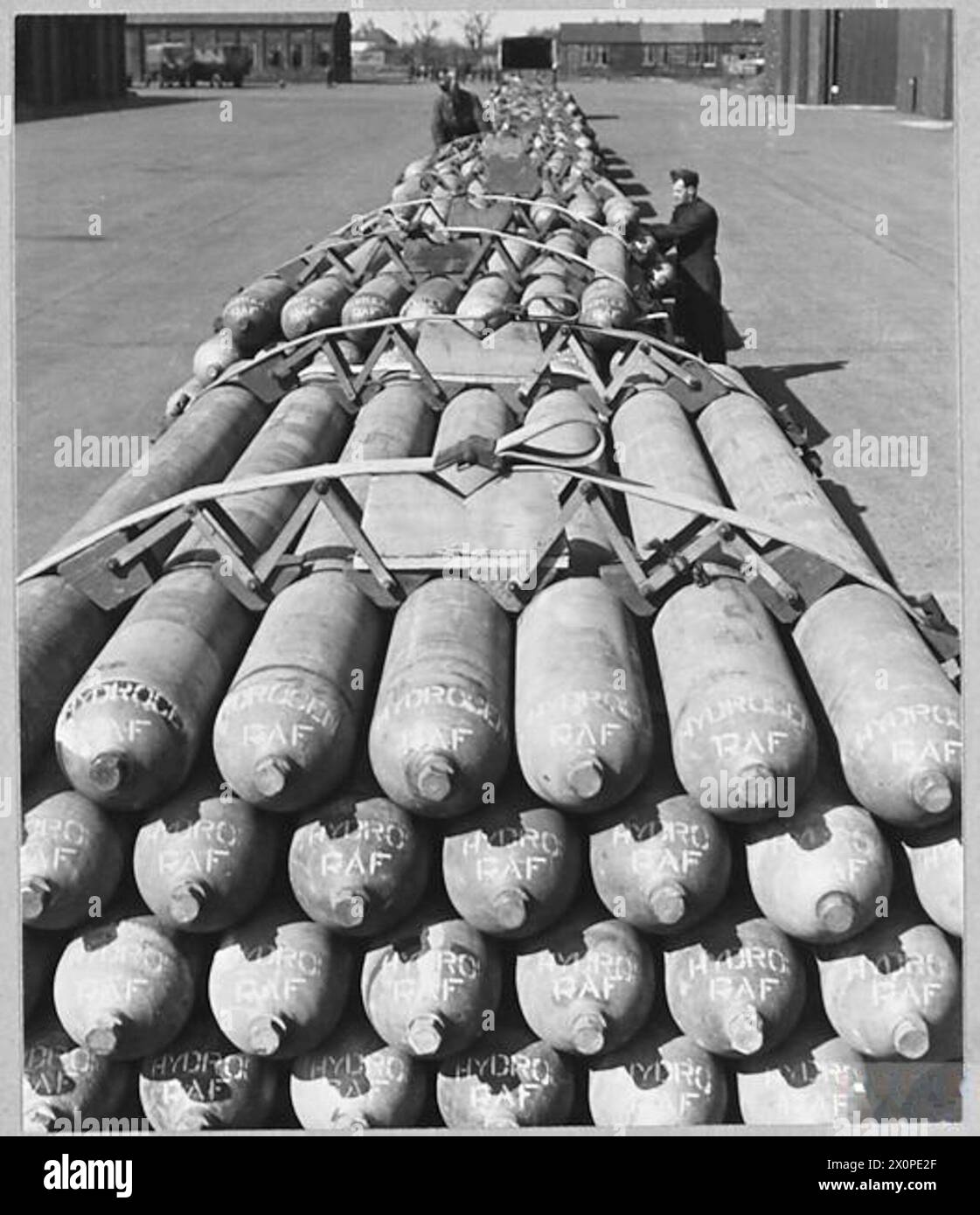 INVASIONSBALLONÜBUNGEN. - Für die Geschichte siehe CH.13208. Abbildung (Ausgabe 1944) zeigt: Lange Reihe von Wasserstoffflaschen, die vor dem Verschieben zum Aufblasen von Ballonen an den Kai druckgeprüft werden. Jeder Anhänger trägt 30 Zylinder, jeder Zylinder fasst 550 Kubikfuß. Für die Erstbefüllung eines Ballons werden fünf Zylinder verwendet. Fotografisches negativ, Royal Air Force Stockfoto