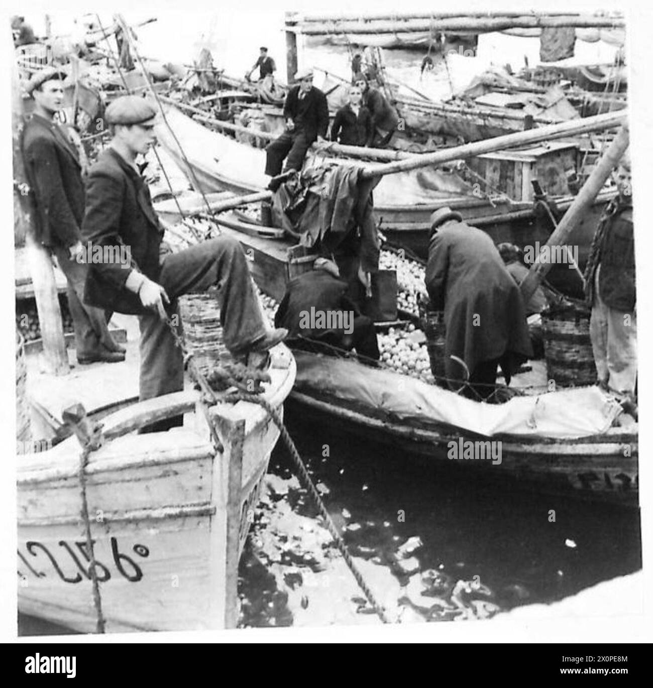 Ein kleines Schiff im Hafen von Piräus, Athen, liefert eine Ladung Orangen, die für die griechische Zivilbevölkerung wichtig ist, während das normale Leben fortgesetzt wird. Stockfoto