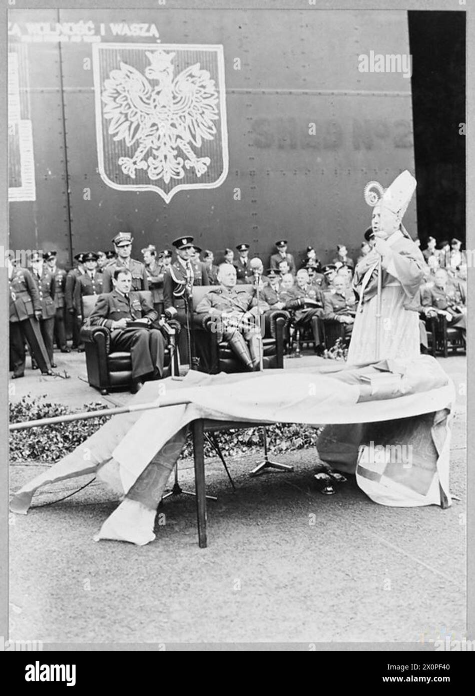 Der neue polnische Luftwaffenstandard, der in Wilno unter sowjetischer Besatzung hergestellt und über Schweden nach Großbritannien geschmuggelt wurde, wird am 16. Juli 1941 auf der RAF Swinderby vorgestellt. Luftmarschall Charles Portal und General Władysław Sikorski hören die Lobrede von Erzbischof Józef Gawlina. Fotografisches negativ, polnische Luftwaffe. Stockfoto