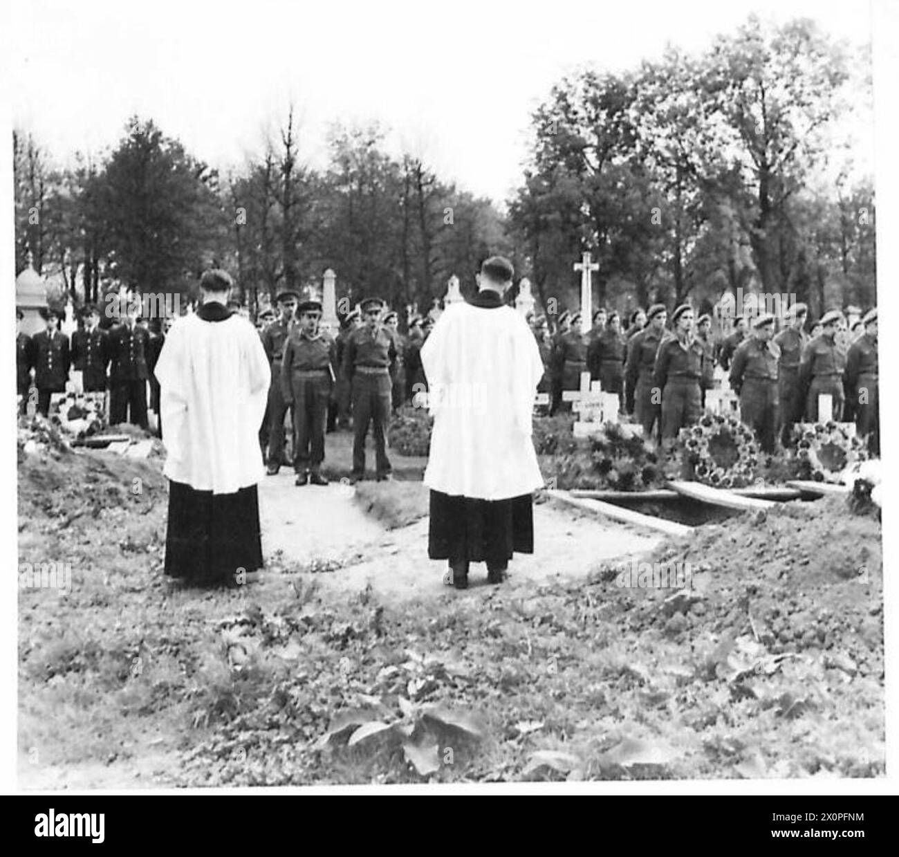 Die Beerdigungsfeier für die Opfer der abgestürzten Befreier in Evere wird von padres Skelton und Senior zusammen mit Colonel Peake und Brigadier Fanshaw besucht, um militärische zeremonielle Praktiken zu dokumentieren. Stockfoto