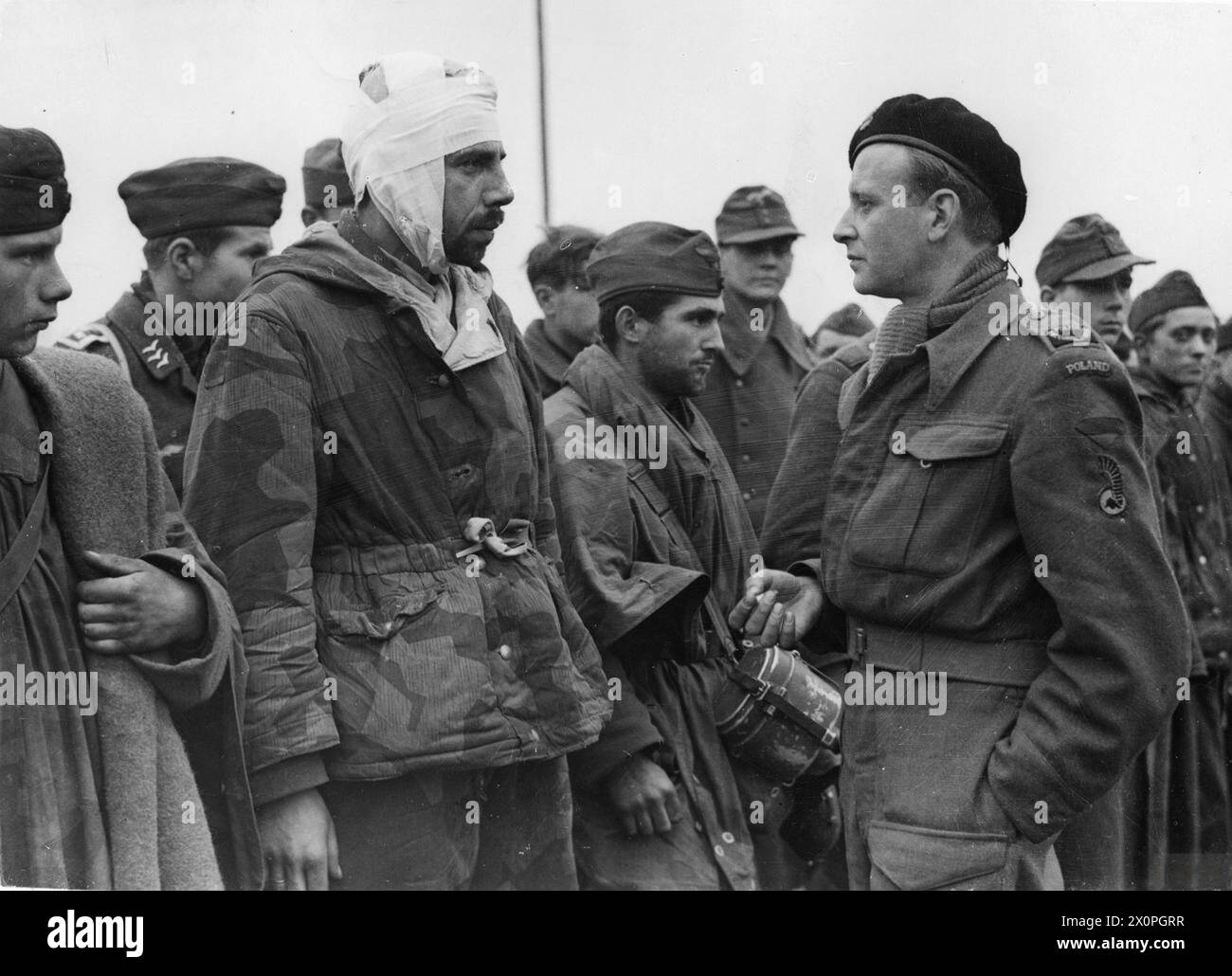 Ein verwundeter deutscher Gefangener in Tarnfarbe, der in Gilze gefangen genommen wurde, wird von dem Kriegsberichterstatter Ryszard Kiersnowski, der der 1. Polnischen Panzerdivision angehört, an der Breda-Tilburg-Front nach der Eroberung von Alphen und Gilze am 27. Oktober 1944 interviewt. Stockfoto